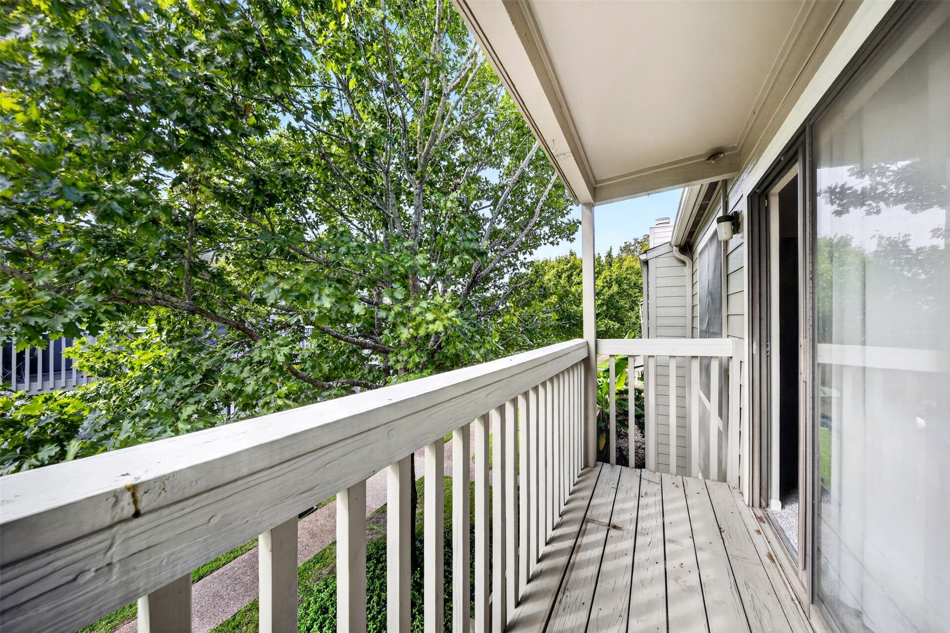 2379 Briarwest Boulevard, #85, Houston, TX 77077 A second covered balcony off the front of the unit, with a wood deck and railing facing mature trees and the community walkway.