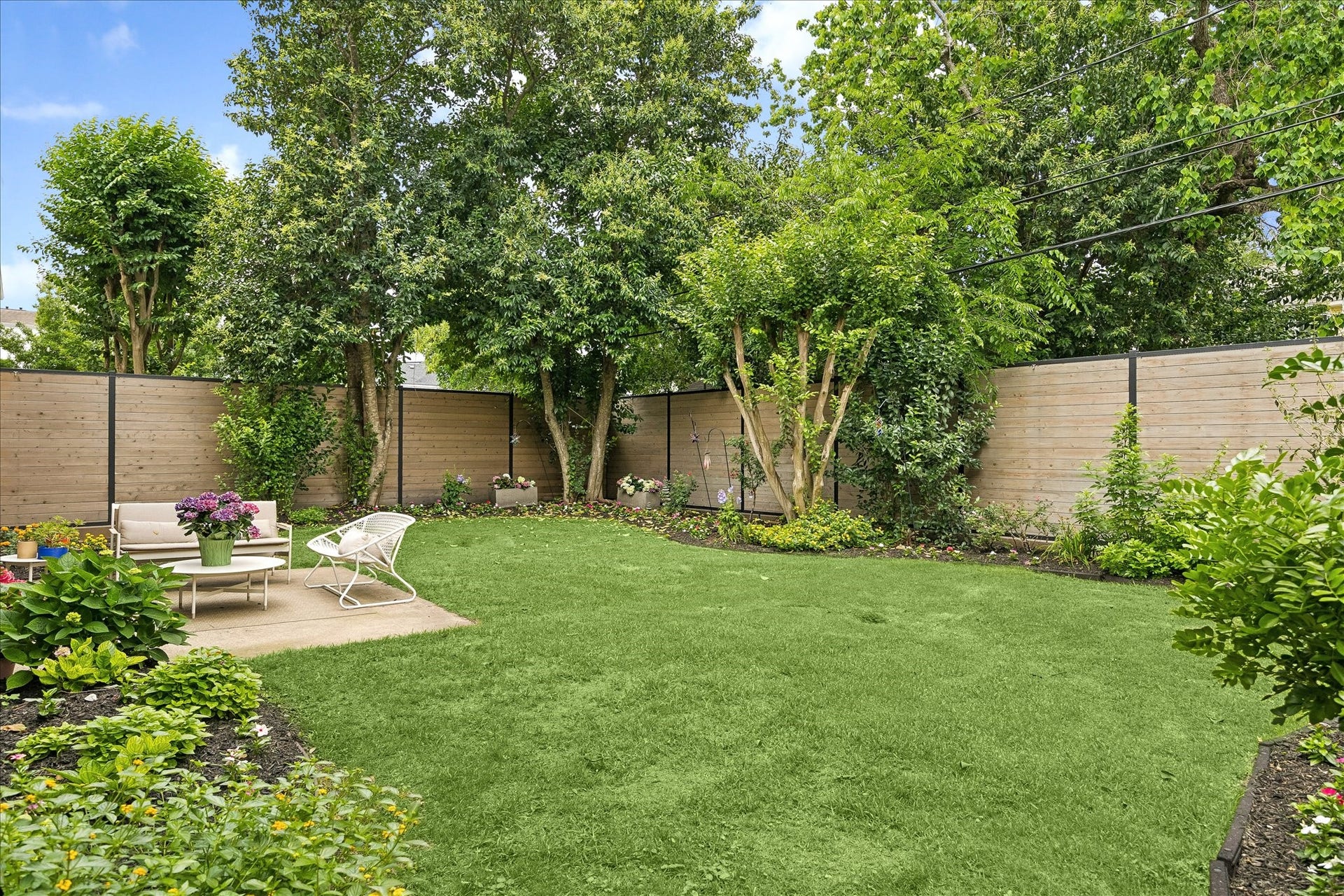 This view of the yard from the southeast corner shows how lush and mature the backyard feels.  Mounted along the perimeter at the top of the fence is a professional mosquito system.
