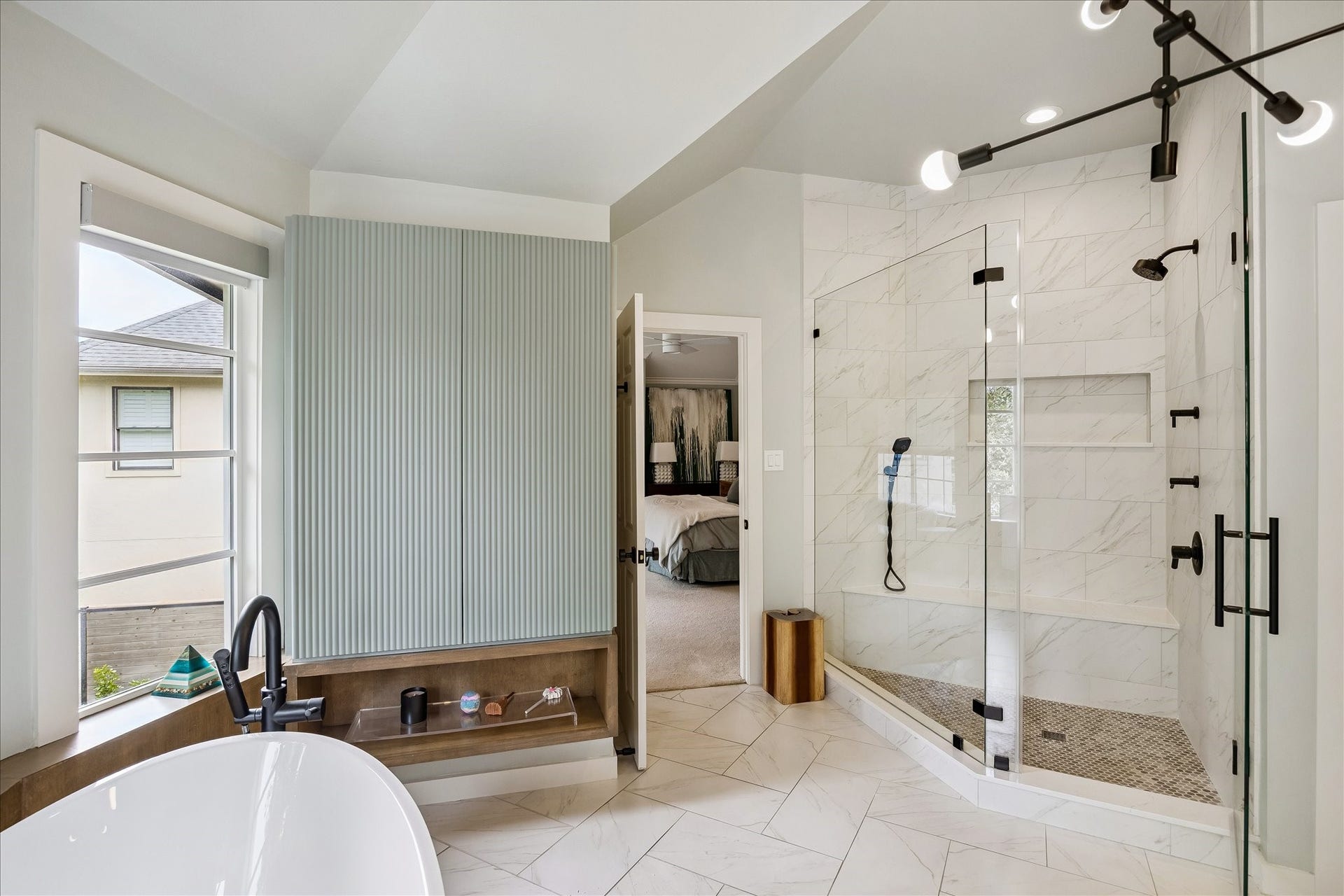 A large shower with the Statuario Maximus by Caesarstone installed within the enclosure that included a seated bench and shampoo niche behind the frameless glass.