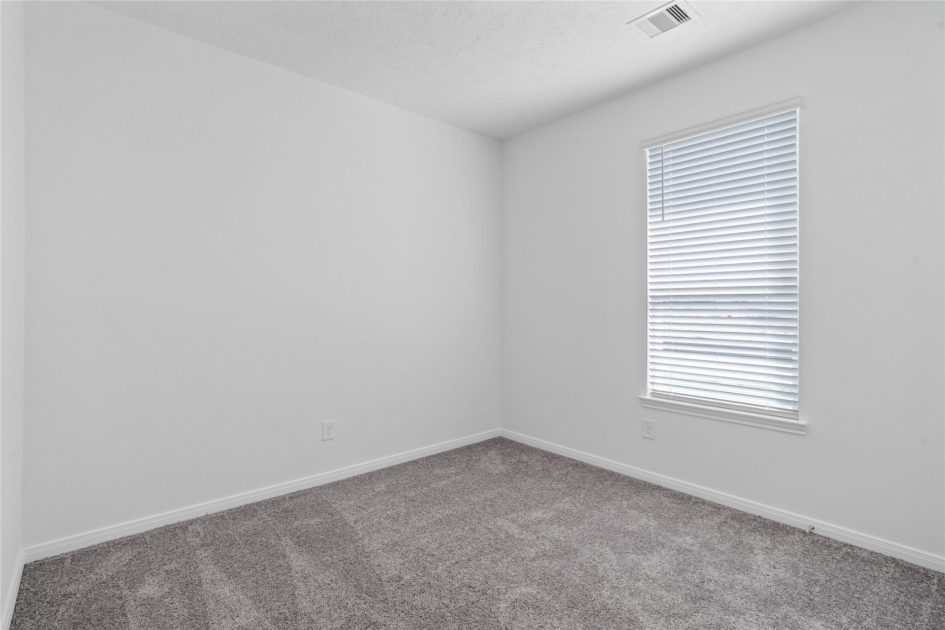 Tucked peacefully in the front of the home is this secondary bedroom. It features plush carpet flooring, large window with blinds, and closet space.