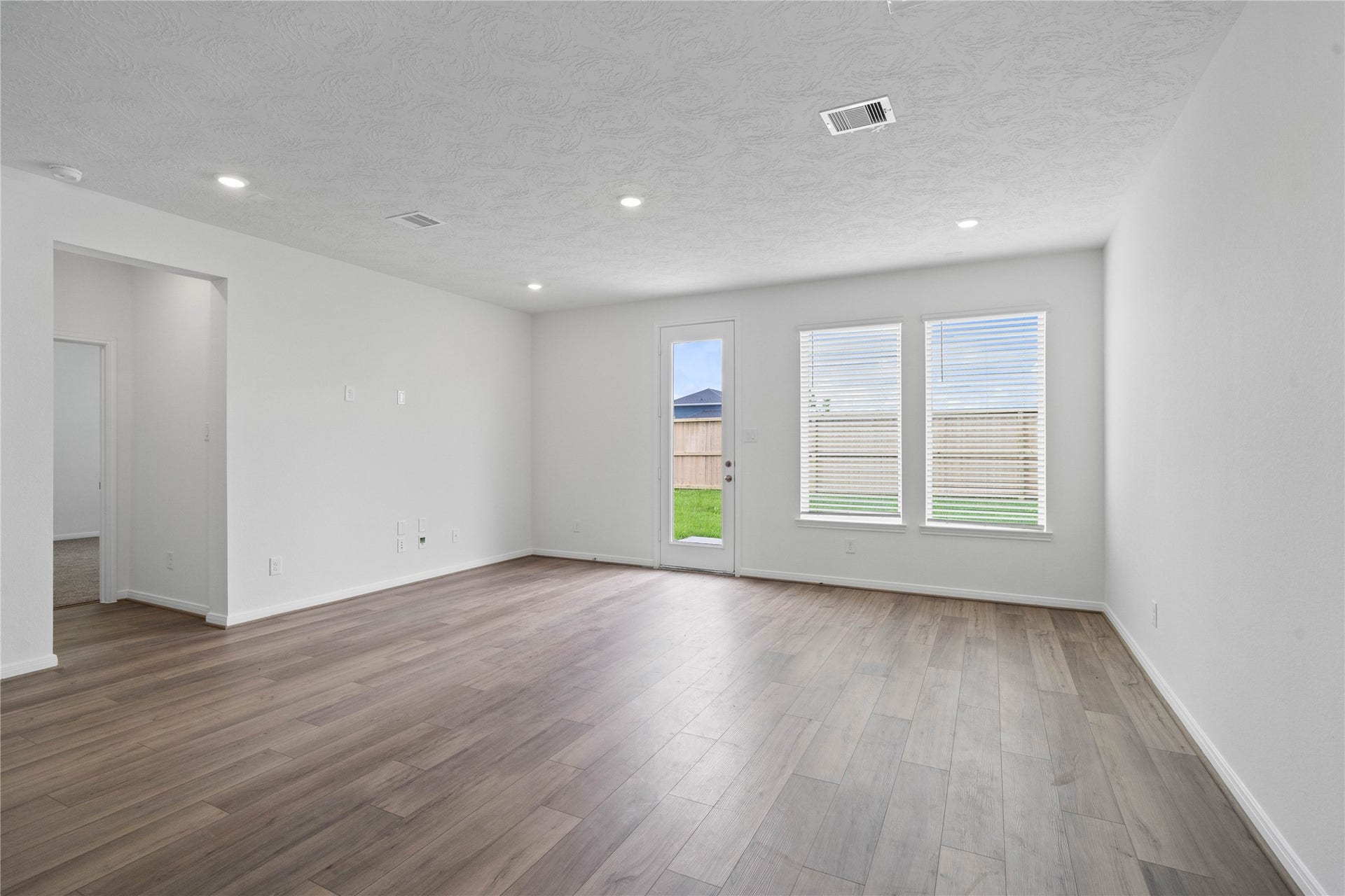 Bring family and friends together in this beautiful Great Room! It features high ceilings, recessed lighting, custom paint, vinyl plank flooring, and large windows that fill the space with natural light all day long.