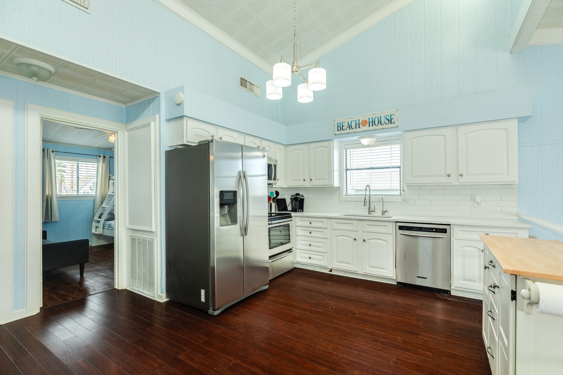 Bright kitchen features white cabinetry, subway tile backsplash, stainless steel appliances, generous counter space, and vaulted ceilings accented by contemporary pendant lighting.