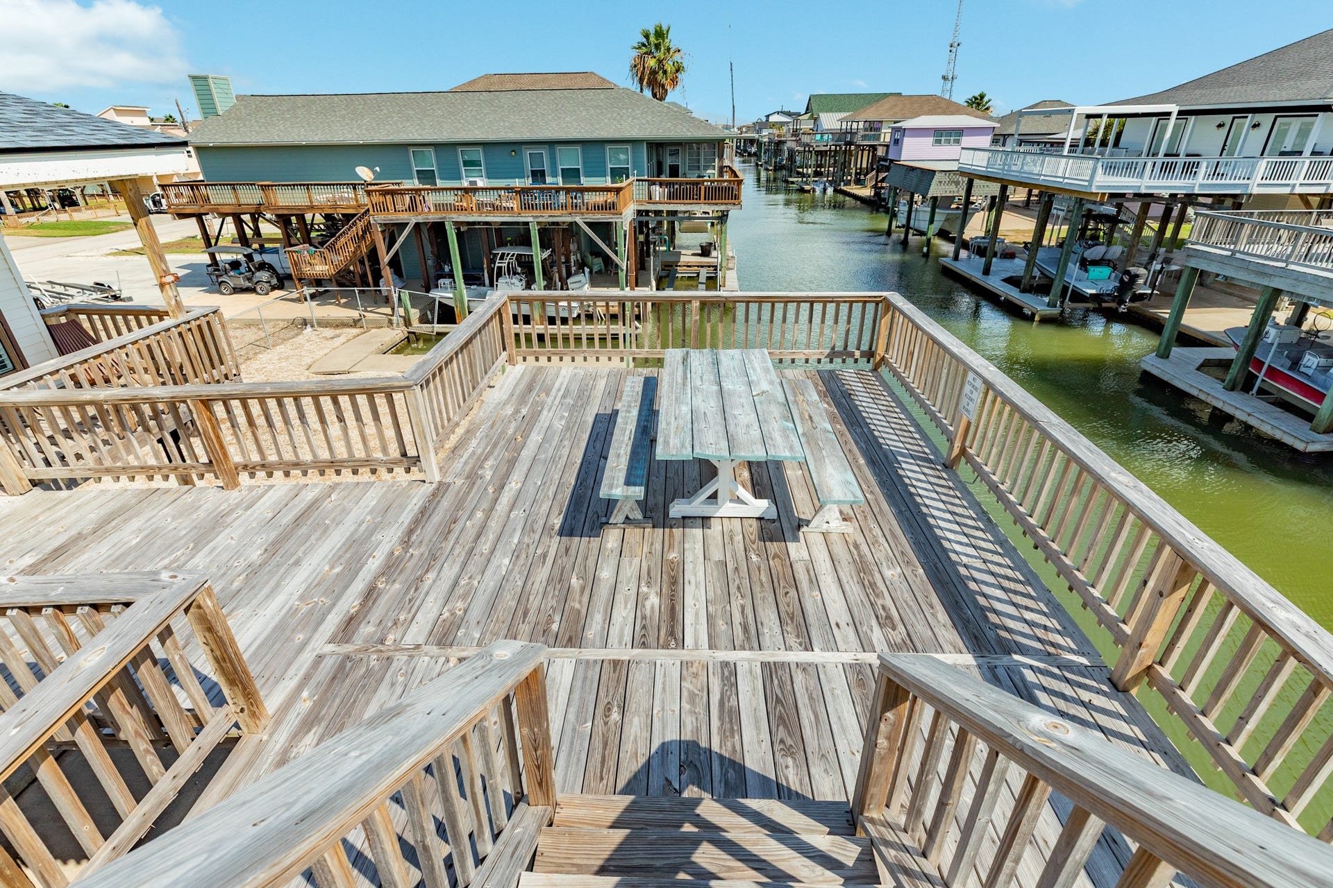 Generous deck overlooking the canal features a picnic table and wooden railings, creating an inviting setting for outdoor meals and waterfront gatherings.