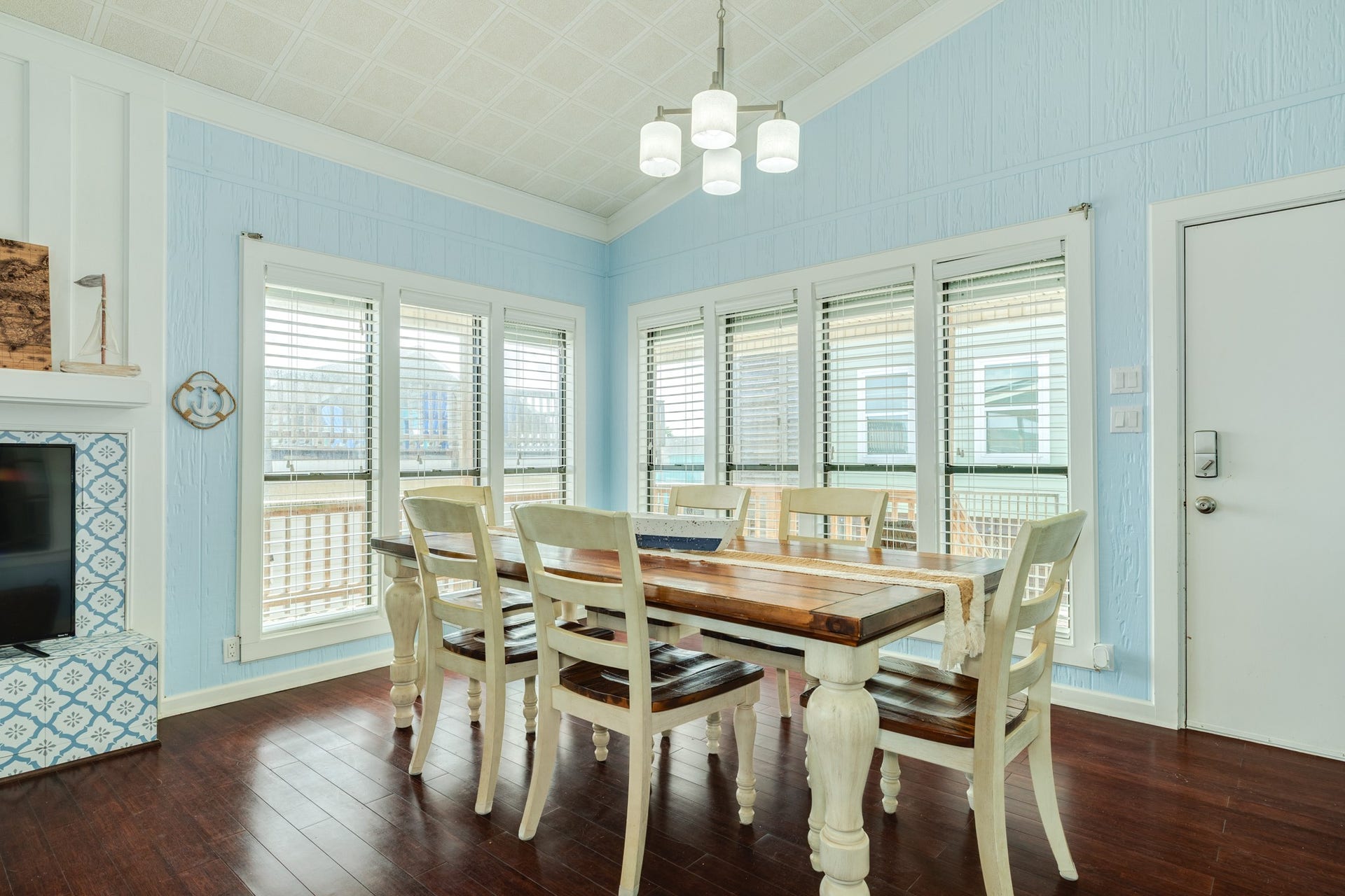 Light-filled dining space features vaulted ceilings, modern pendant lighting, and large windows with views of the surrounding neighborhood, creating an inviting setting for meals and entertaining.
