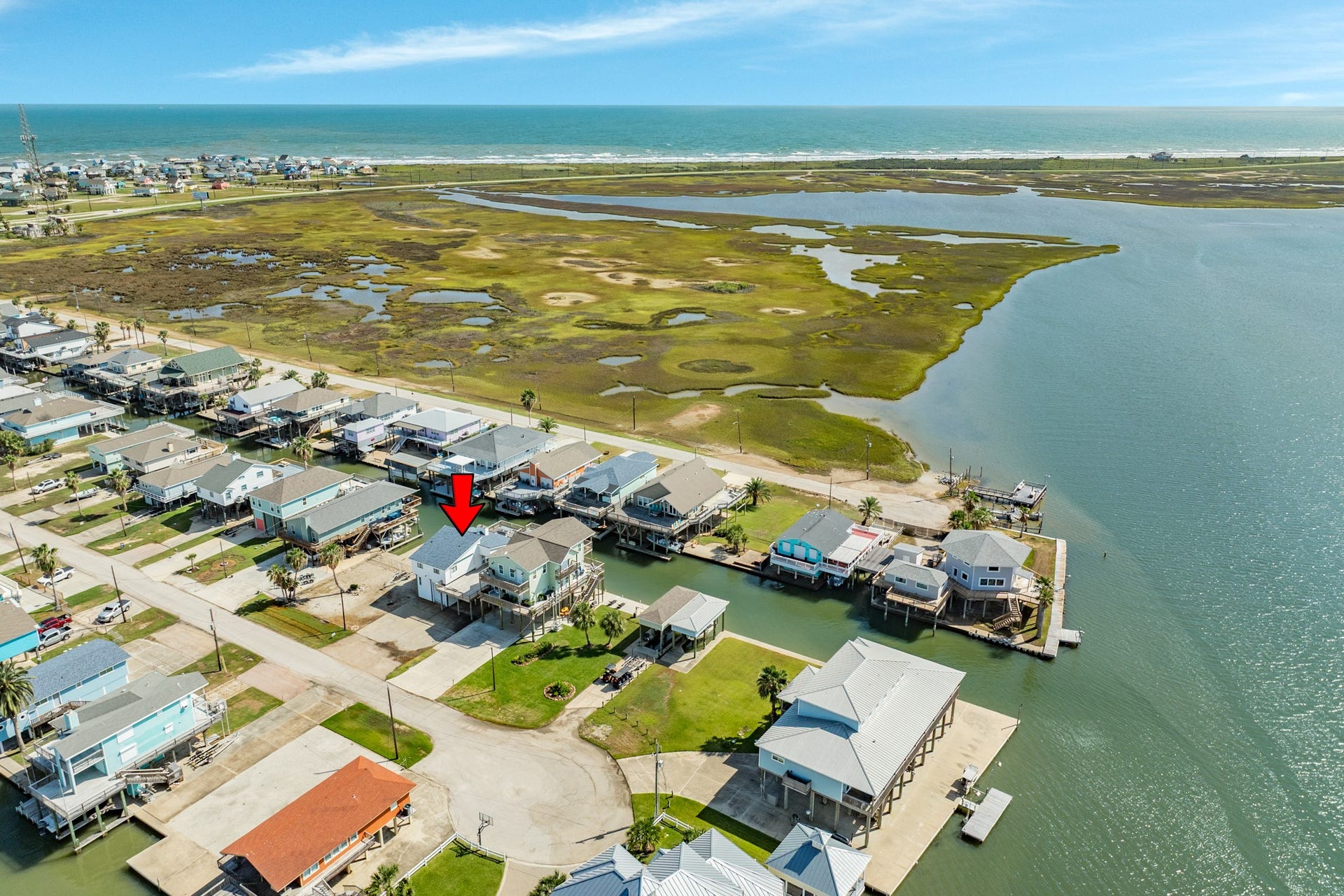 Sweeping aerial view showcases the coastal neighborhood, winding canals, nearby bay waters, and the bridge leading toward the Gulf shoreline.
