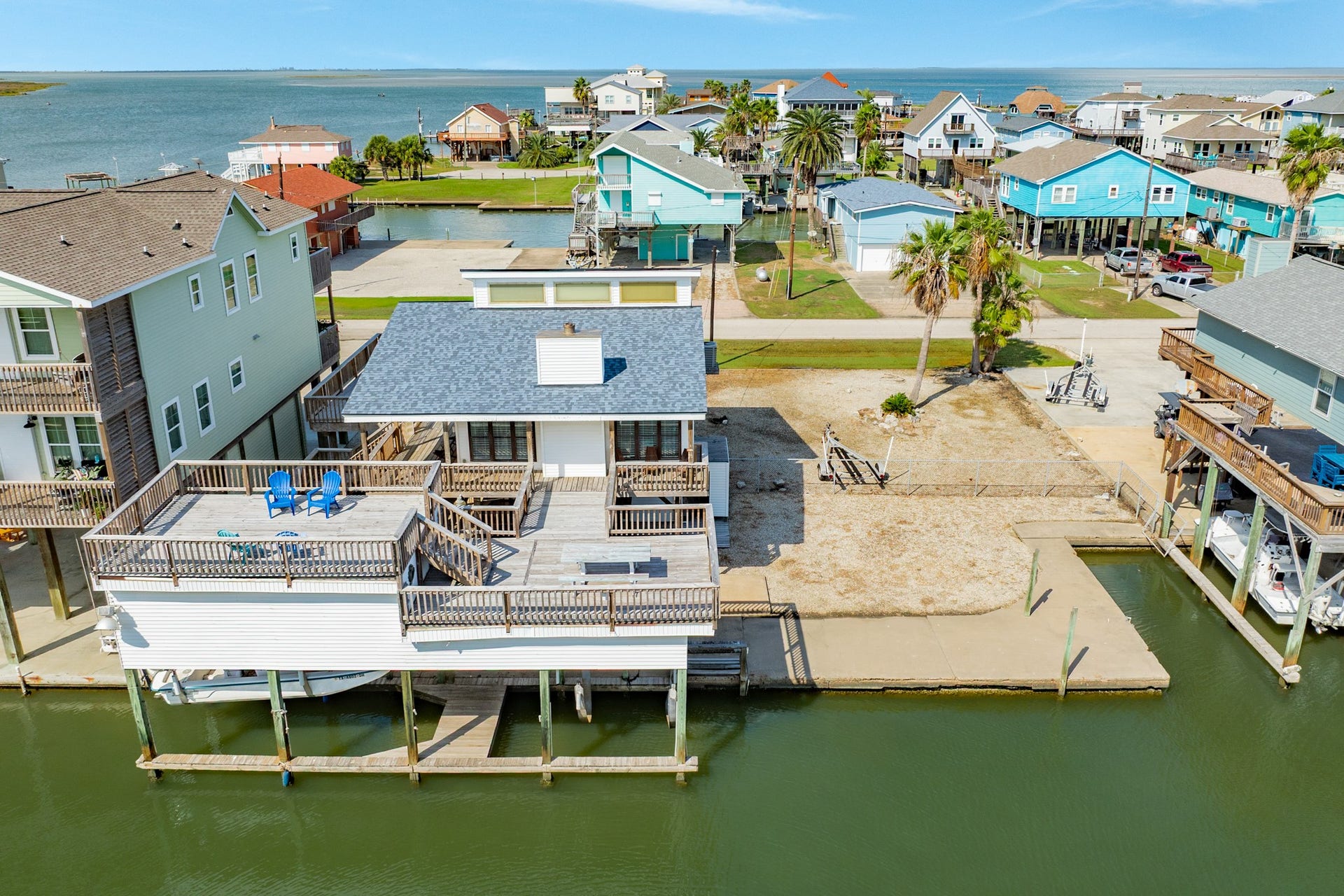 Stunning aerial perspective showcases the canal-front property with expansive waterfront decking, a covered boat slip, and a spacious lot surrounded by coastal scenery.