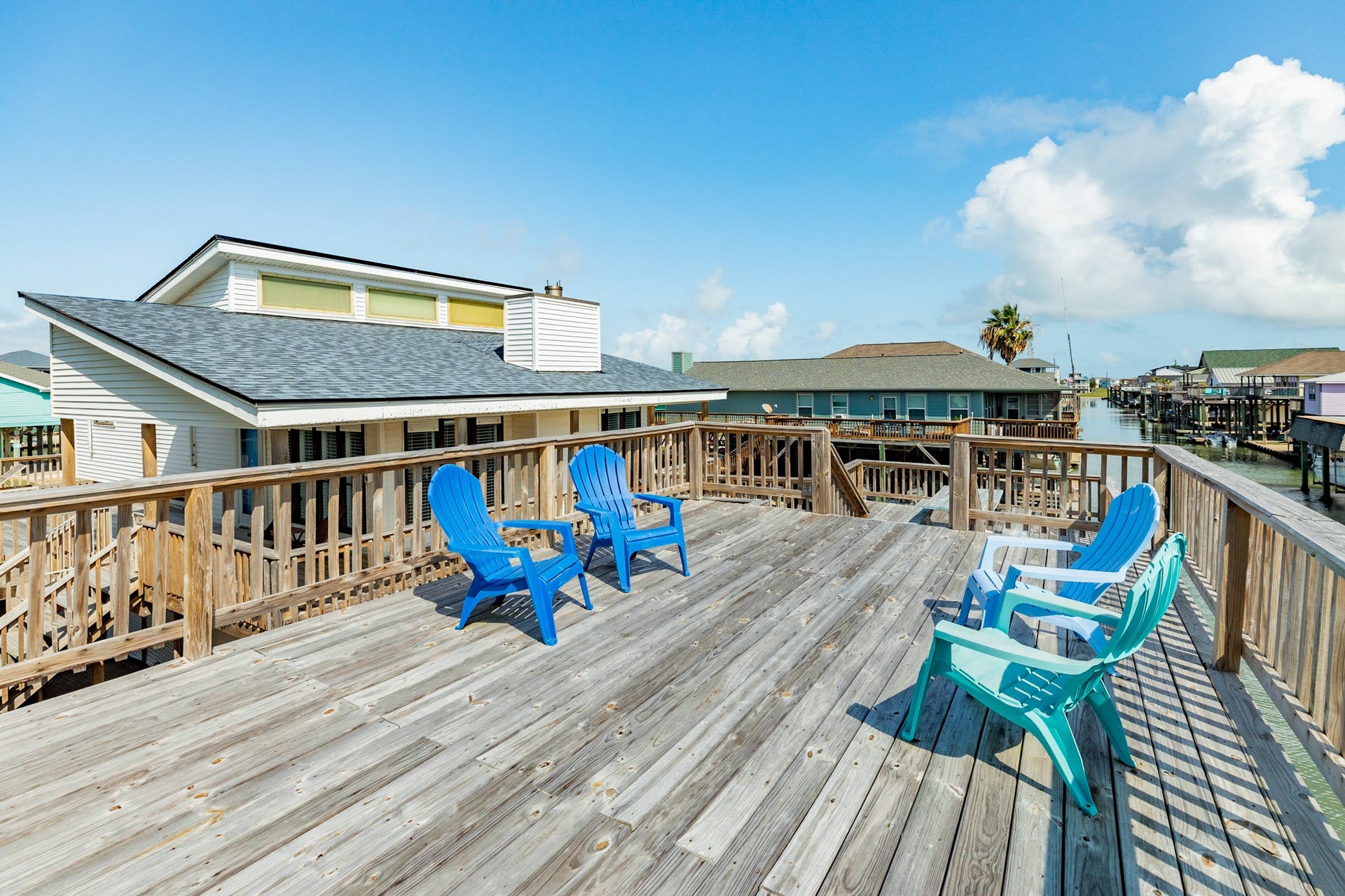 Spacious elevated deck offers plenty of room for outdoor seating and entertaining, with colorful Adirondack chairs and scenic canal views.