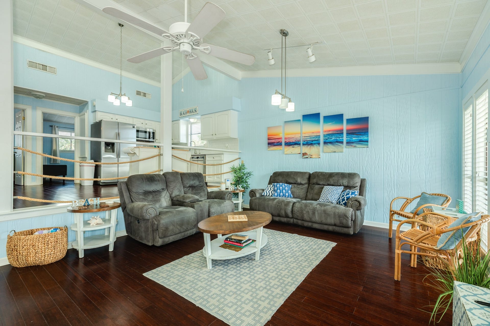 Spacious living area flows into the kitchen and features vaulted ceilings, dark wood-look flooring, coastal-inspired finishes, and an open layout ideal for everyday living and entertaining.