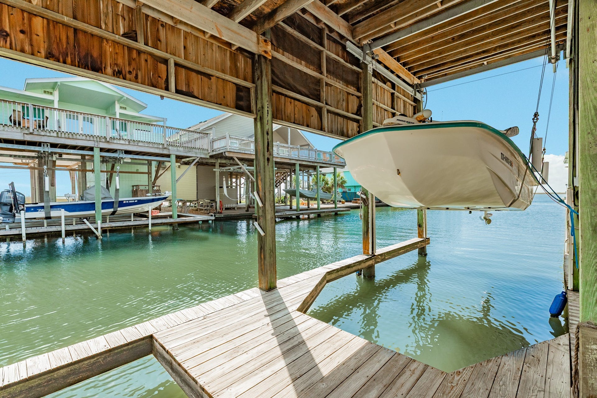 Covered boat lift with wooden decking provides a dedicated space for boat storage and convenient access to the canal, making it easy to enjoy time on the water.