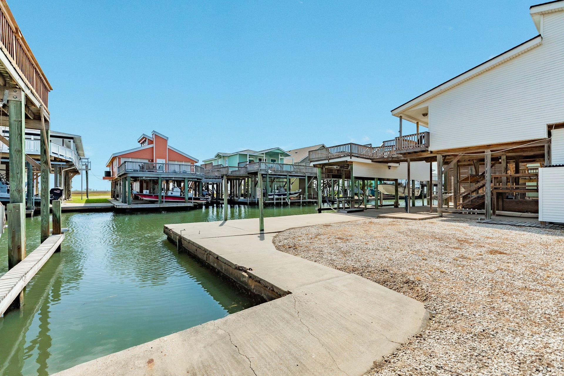 Wide canal-side view highlights the property's concrete waterfront edge, open yard space, and boat lift, providing a versatile setting for enjoying life on the water.