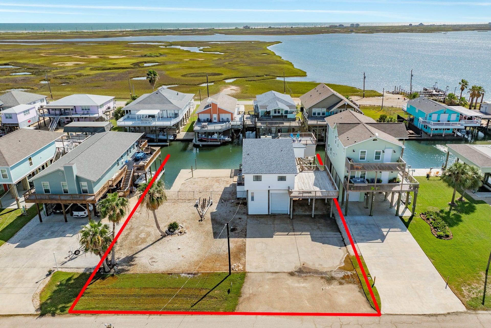 Property boundaries are outlined in this aerial view, highlighting the spacious lot, concrete driveway, canal frontage, and room for outdoor recreation.