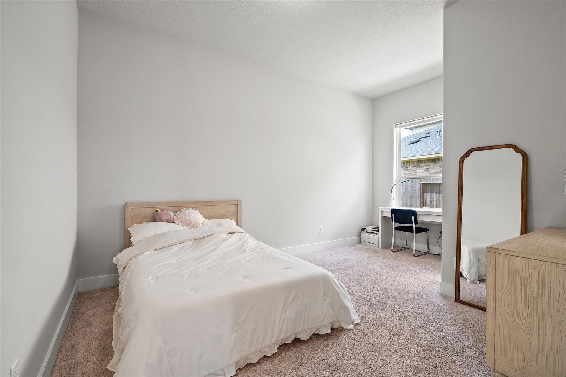 This bedroom offers soft carpeted floors, a window for natural light, and modern dome lighting,  providing a comfortable and airy space.