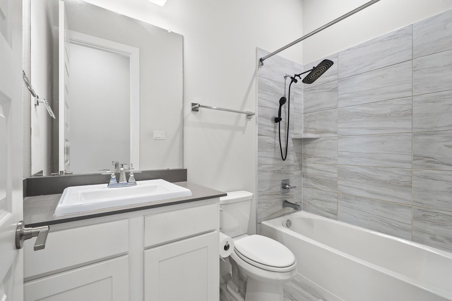 This bathroom boasts a single-sink vanity, a shower/tub combo, and a toilet  a practical and stylish space designed for everyday comfort.