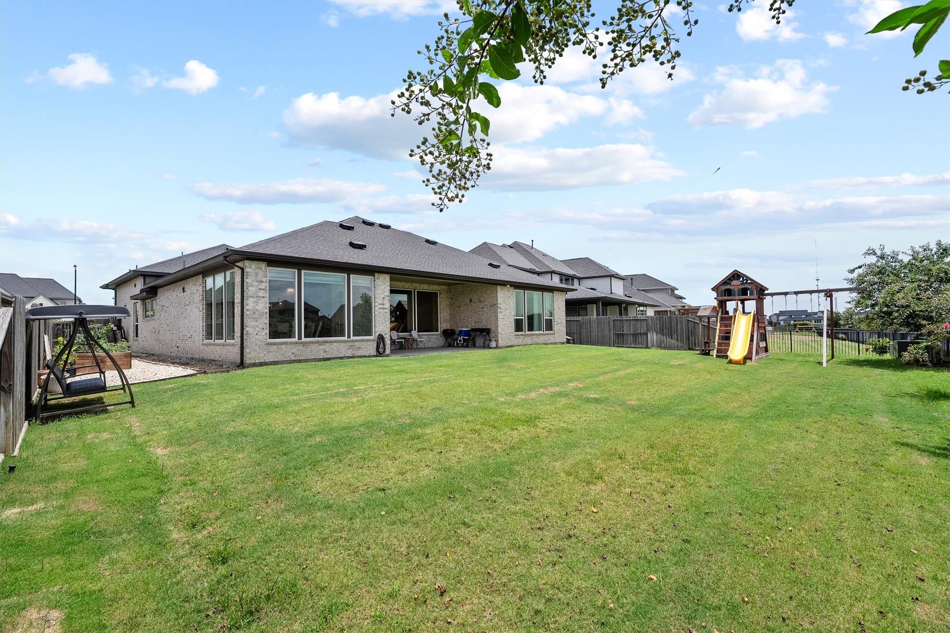 Enjoy another view of the spacious backyard, showcasing a spacious covered patio, a garden area and a lush green lawn that creates a serene and inviting outdoor retreat.