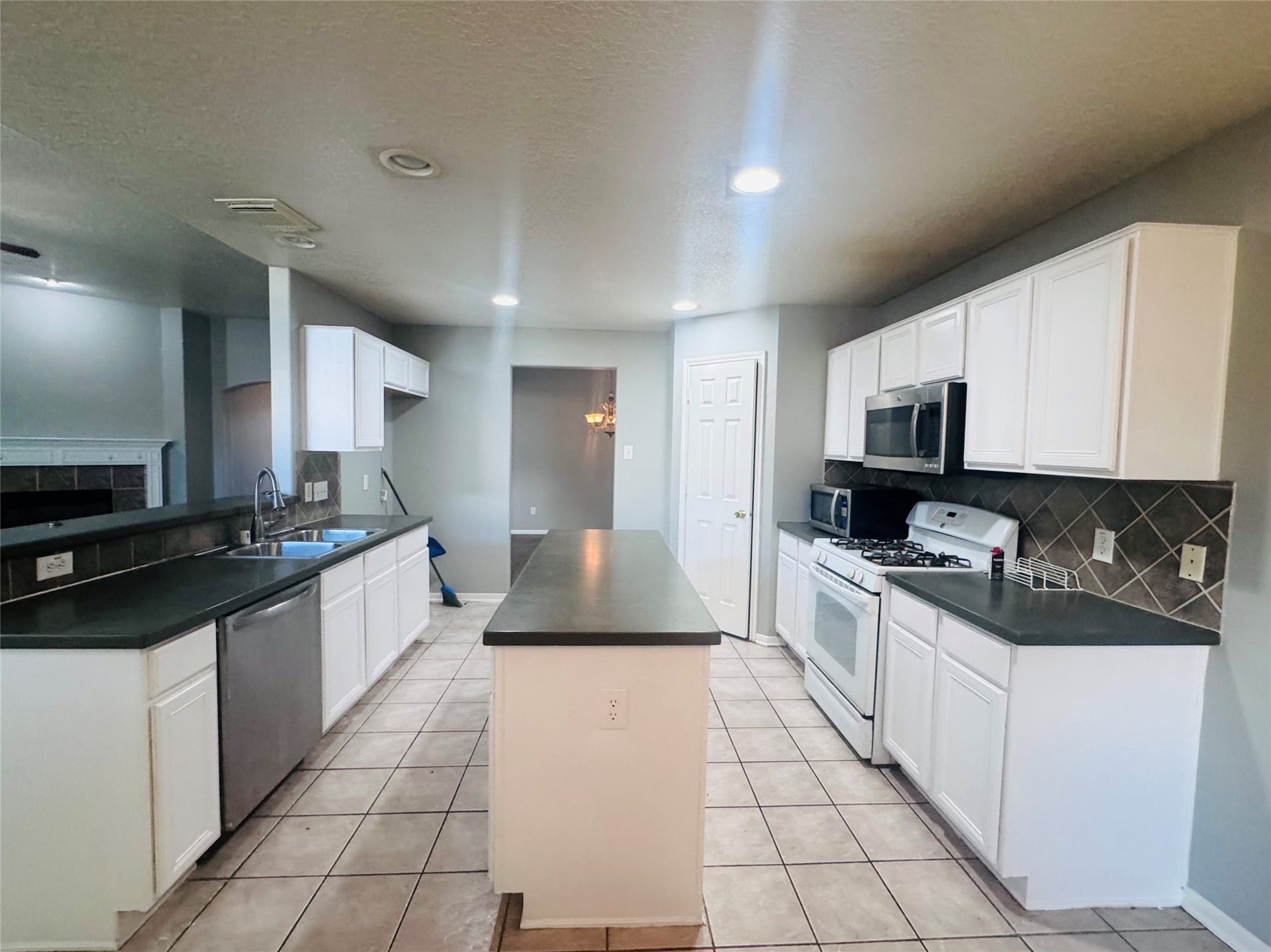 Spacious kitchen with sleek countertops, modern stainless steel appliances, and ample white cabinetry, perfect for culinary enthusiasts.