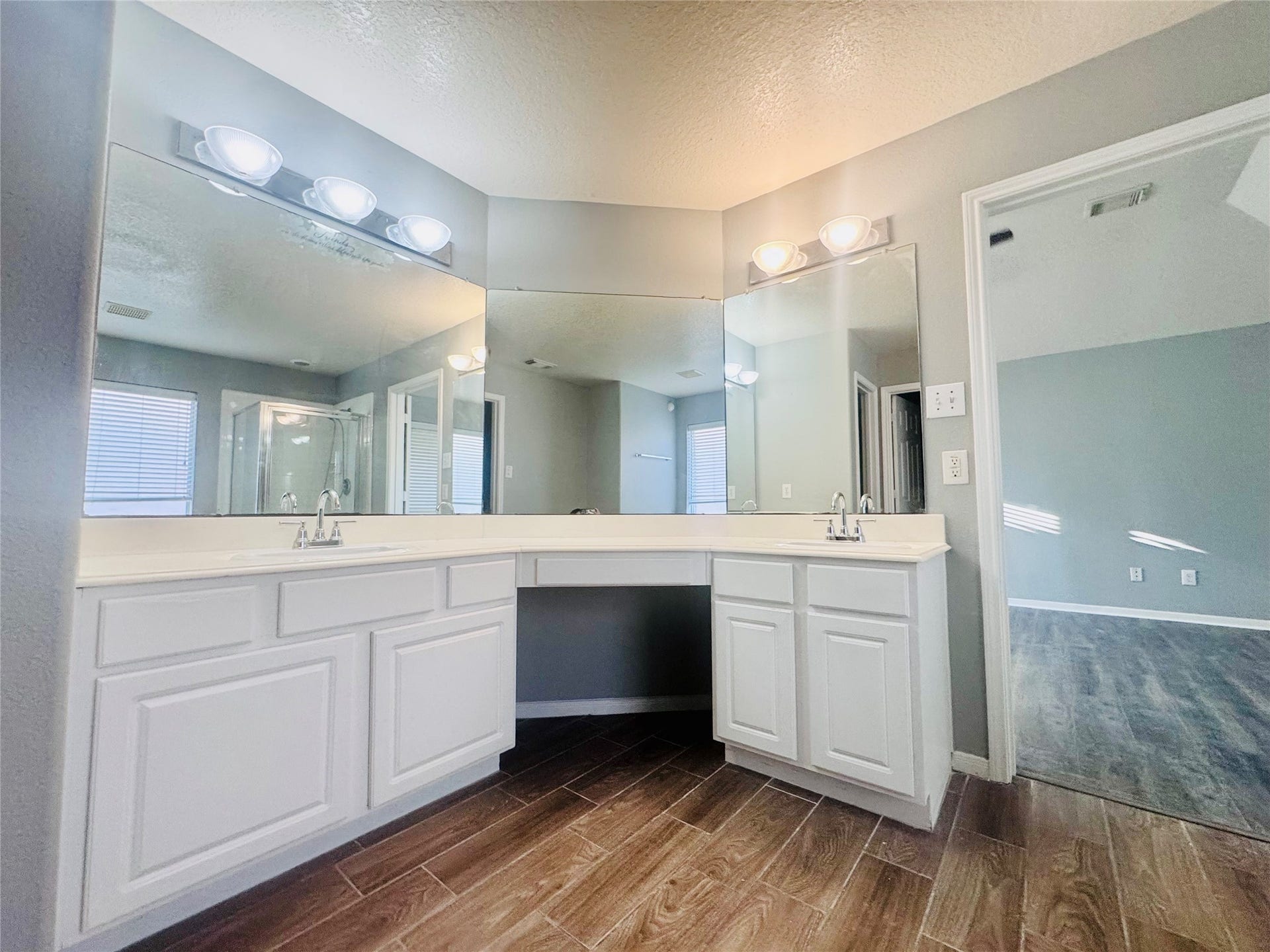 Spacious primary bathroom with a dual-sink vanity, large mirrors, and modern lighting.