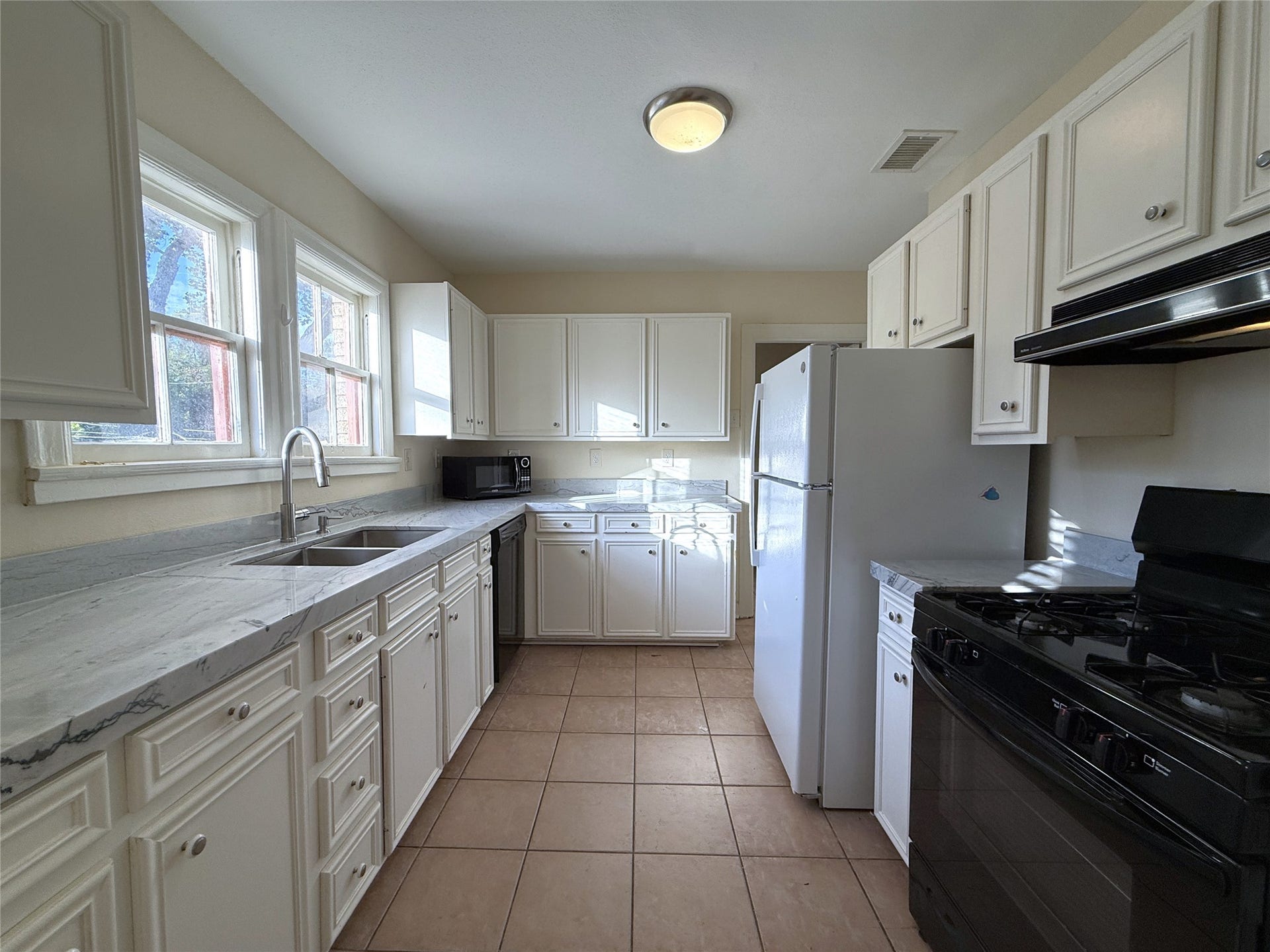 1968 Dryden Road, #2, Houston, TX 77030 The spacious kitchen offers stone counter tops, dishwasher, gas cooking and lots of storage space. Natural light flows in from twin windows above the sink.
