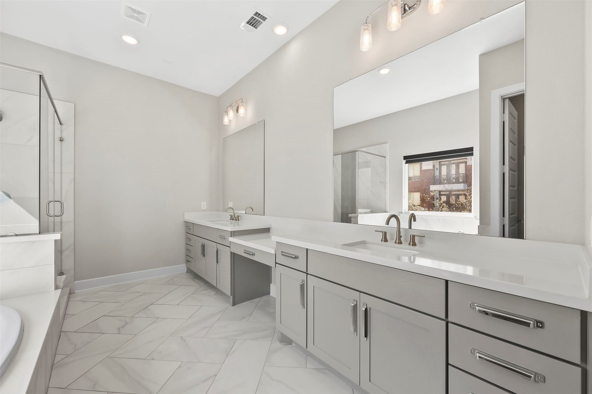 Spacious primary bathroom with extended dual vanity, abundant storage, and contemporary finishes.