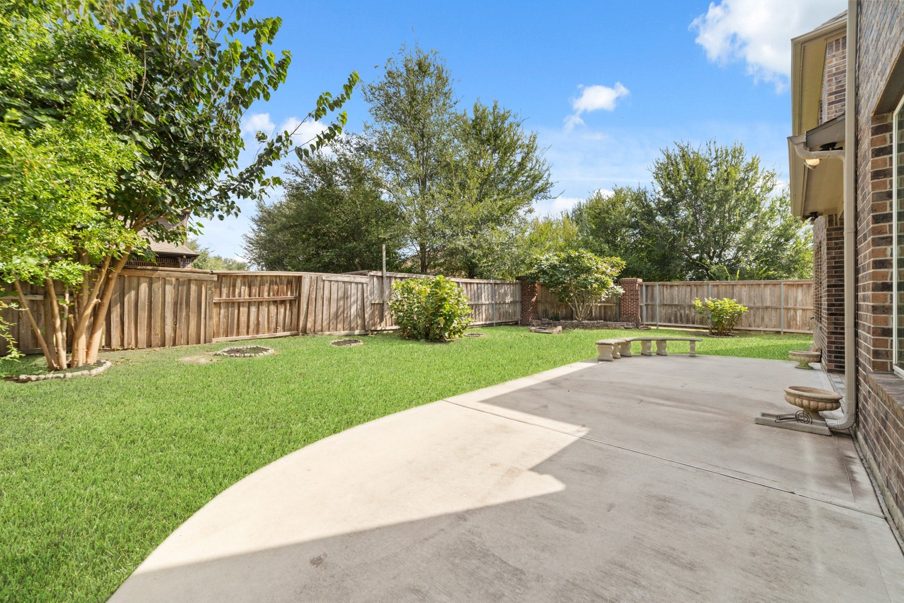17302 Milrig Court, Richmond, TX 77407 Spacious backyard featuring a well-maintained lawn, mature trees, and a large patio perfect for outdoor entertaining.