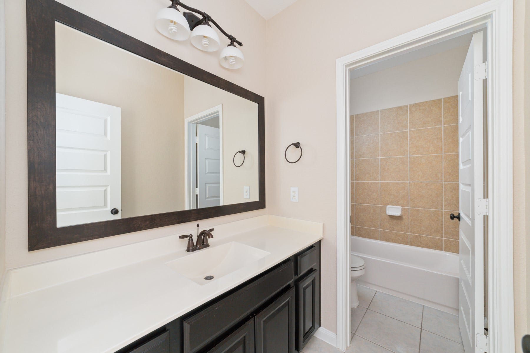 17302 Milrig Court, Richmond, TX 77407 Upstairs Bathroom #3 offers a modern retreat with its sleek vanity, expansive mirror, and inviting tiled bathtub, perfect for unwinding.