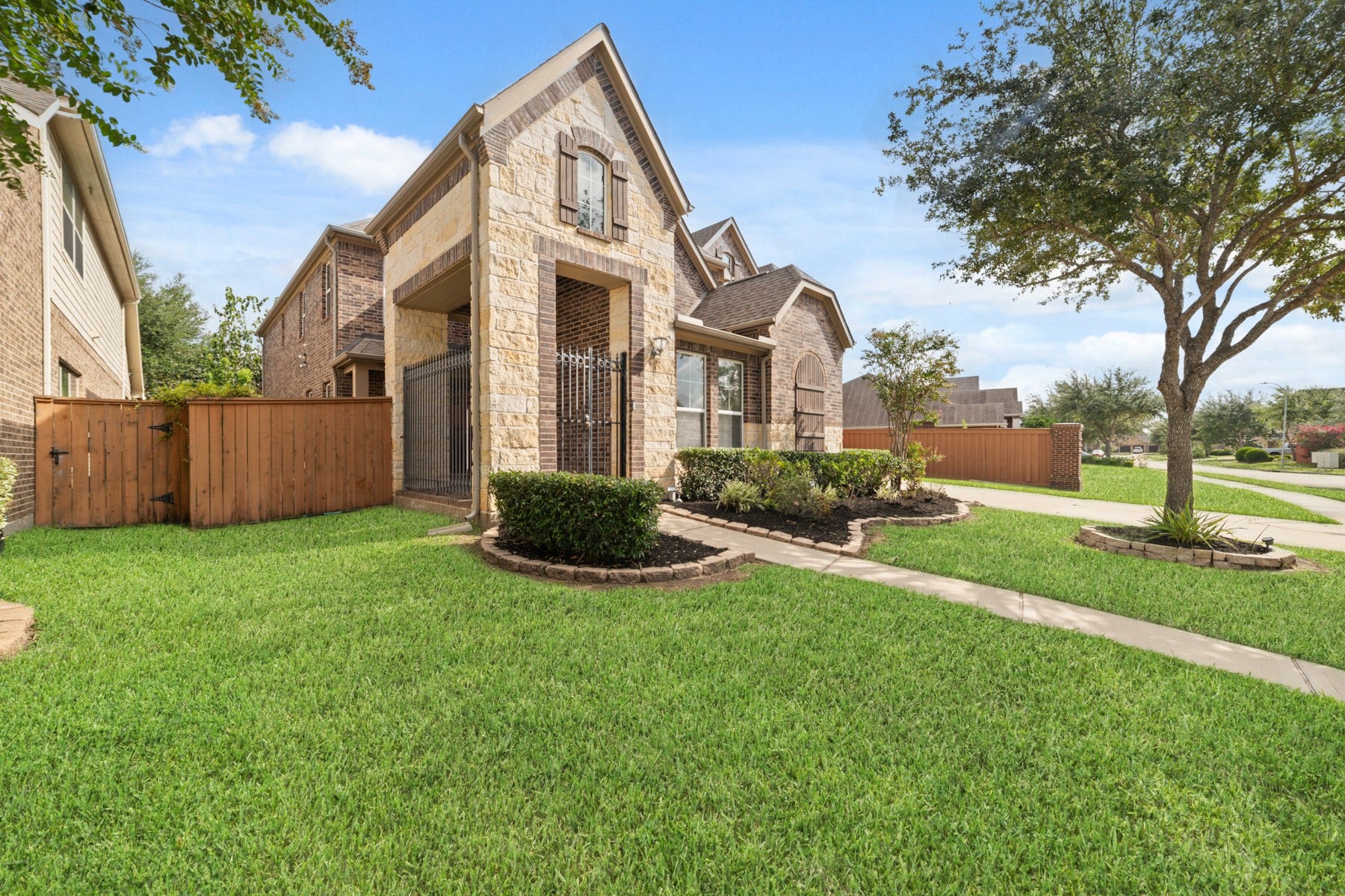 17302 Milrig Court, Richmond, TX 77407 Charming home with stone and brick exterior, nestled on a corner lot. Beautifully manicured lawn and mature trees enhance the curb appeal.