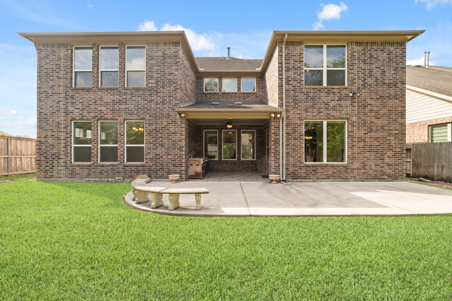 17302 Milrig Court, Richmond, TX 77407 Stunning two-story brick home with expansive windows, a spacious patio for outdoor entertaining, and a lush green lawn. Plenty of space to add an oasis resort pool.