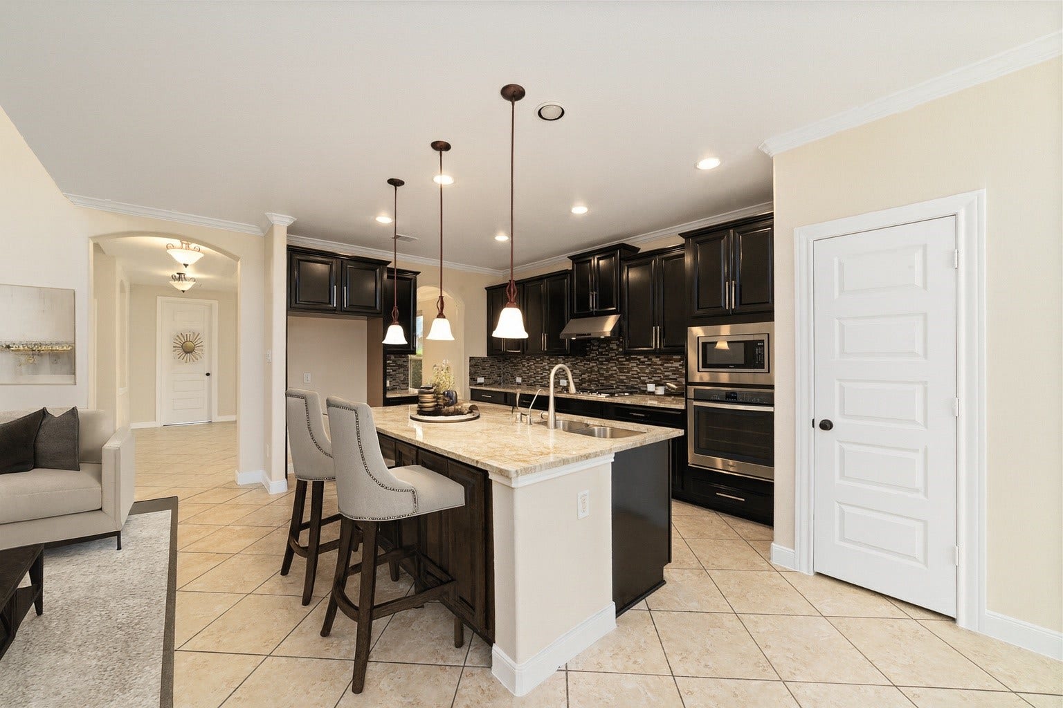 17302 Milrig Court, Richmond, TX 77407 *virtually staged* - Modern elegance defines this sleek kitchen, featuring dark cabinetry, a stunning island with seating, and an open layout designed for effortless entertaining.