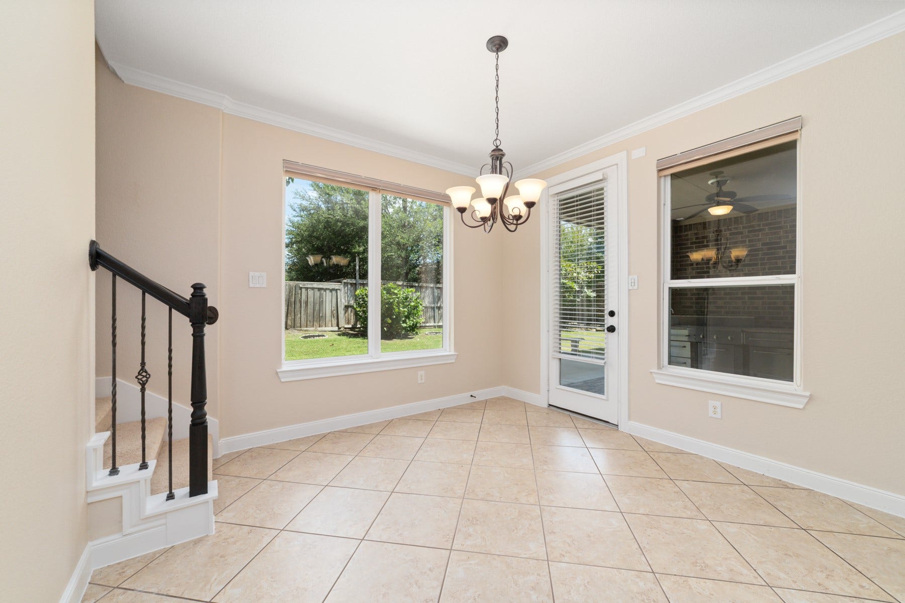 17302 Milrig Court, Richmond, TX 77407 Sunlit breakfast nook with elegant tile flooring and a charming chandelier, offering a perfect spot to enjoy morning coffee with views of the lush backyard.