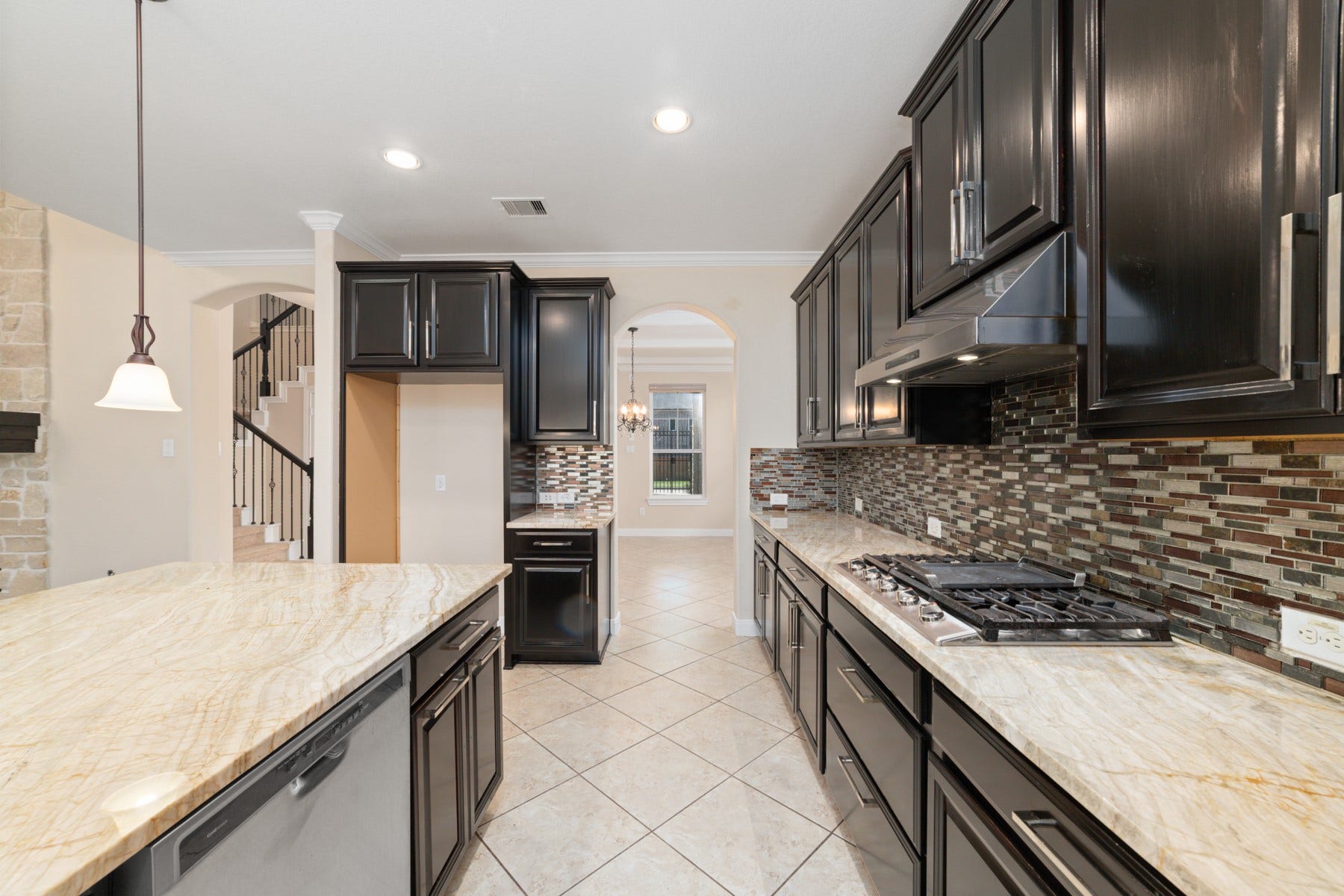 17302 Milrig Court, Richmond, TX 77407 Elegant kitchen featuring sleek dark cabinetry, a stylish mosaic backsplash, and gleaming granite countertops.