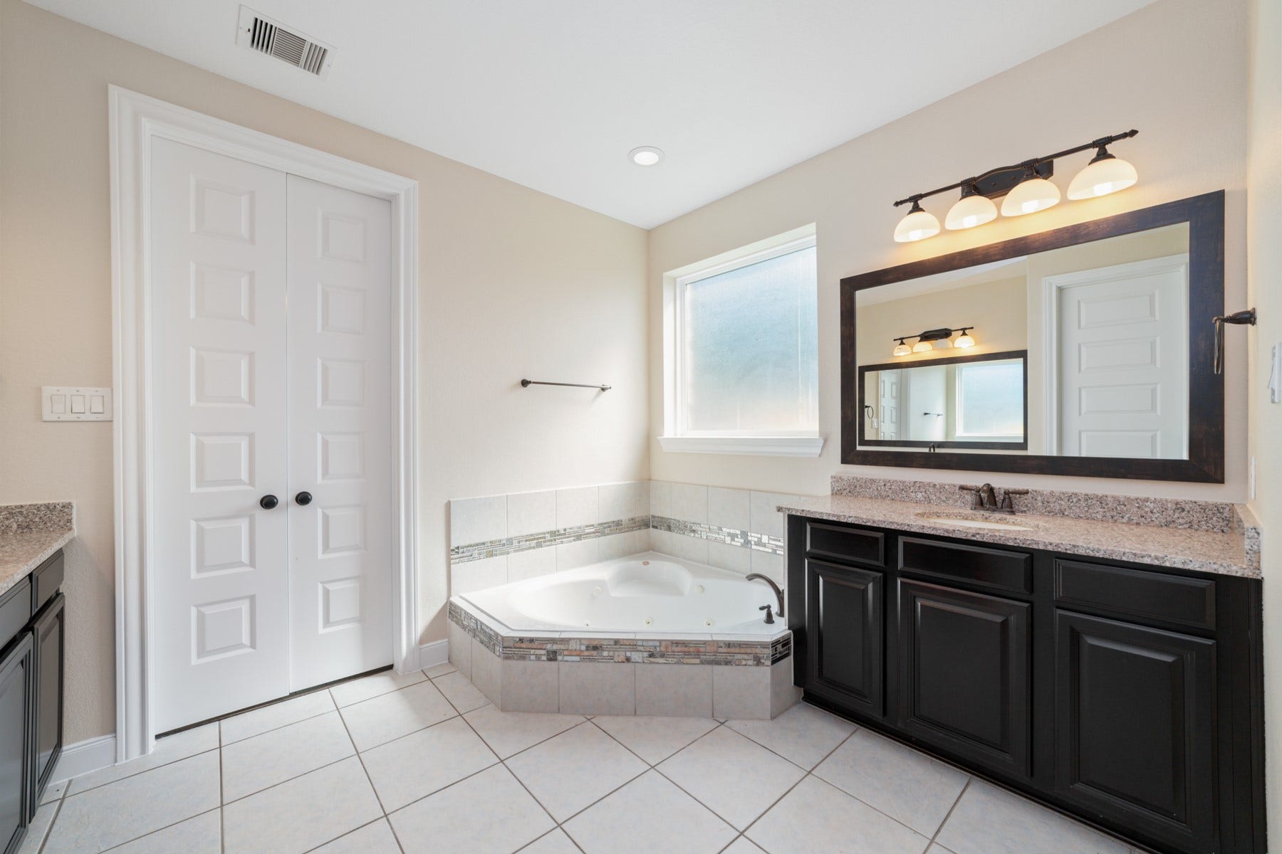 17302 Milrig Court, Richmond, TX 77407 Indulge in relaxation with a spacious primary bathroom featuring a luxurious soaking tub, elegant vanity, and abundant natural light.
