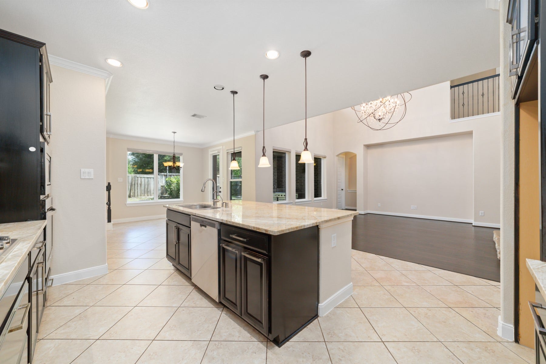 17302 Milrig Court, Richmond, TX 77407 Spacious kitchen with pendant lighting, a large granite island, and open flow to the living area, filled with natural light and modern finishes.