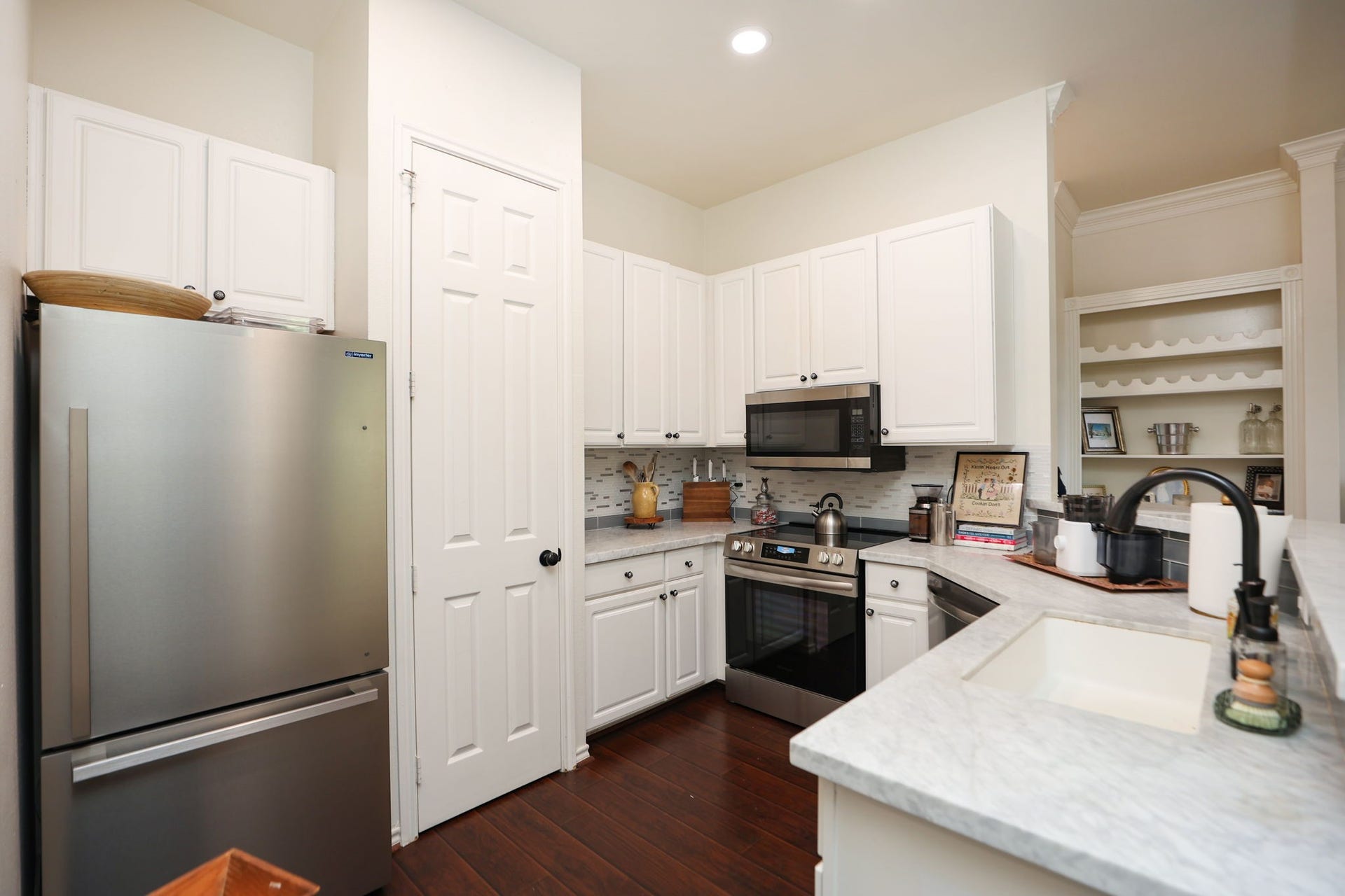 2400 S Mccue Road, #104, Houston, TX 77056 Entry into kitchen showing the updated appliances and Carra Marble Counter Tops along with new wood flooring.