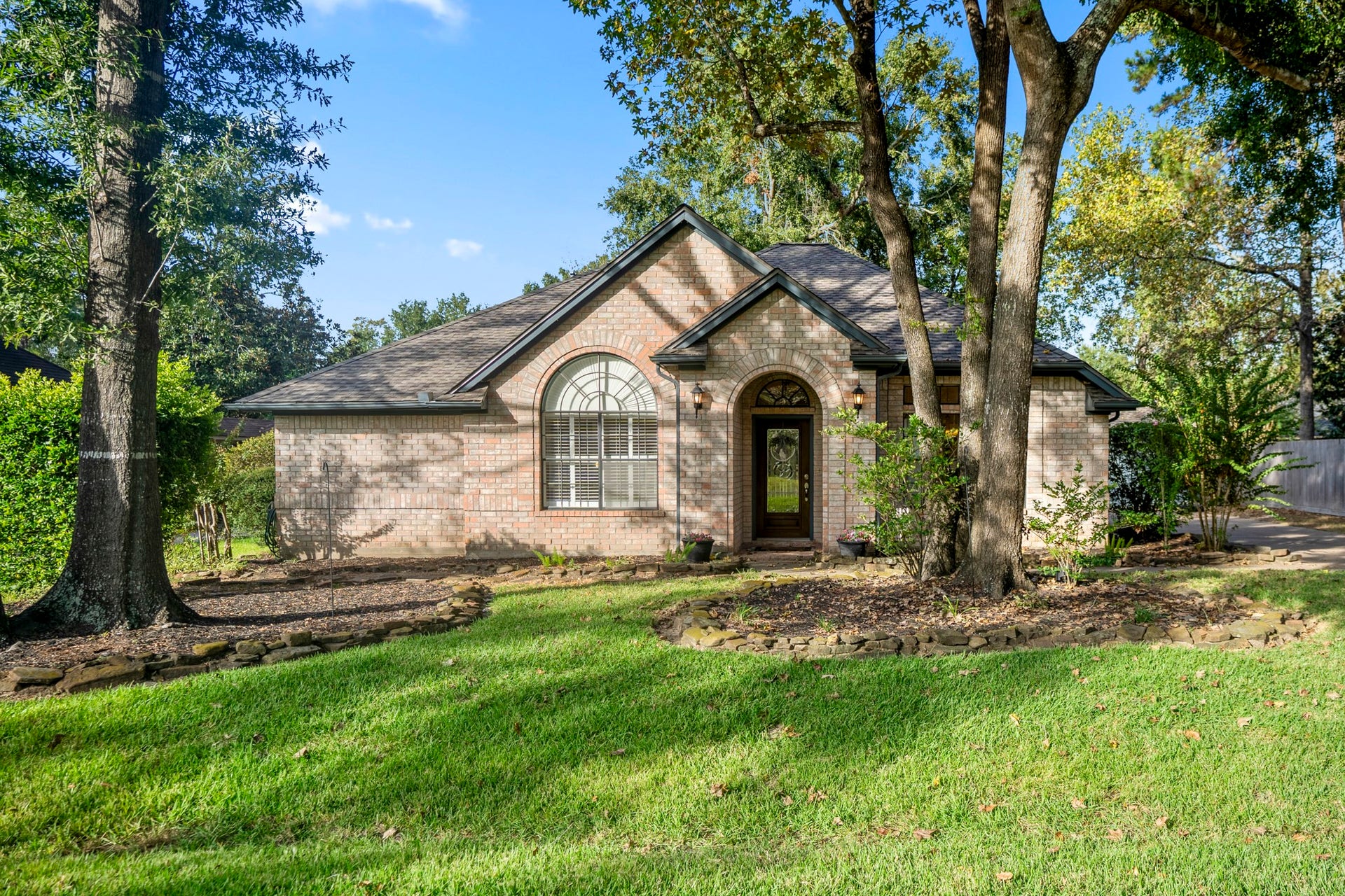 812 Woodland Lane, Conroe, TX 77302 Welcome home! This charming move in ready brick home is tucked beneath mature trees with a long driveway leading to the oversized detached garage.