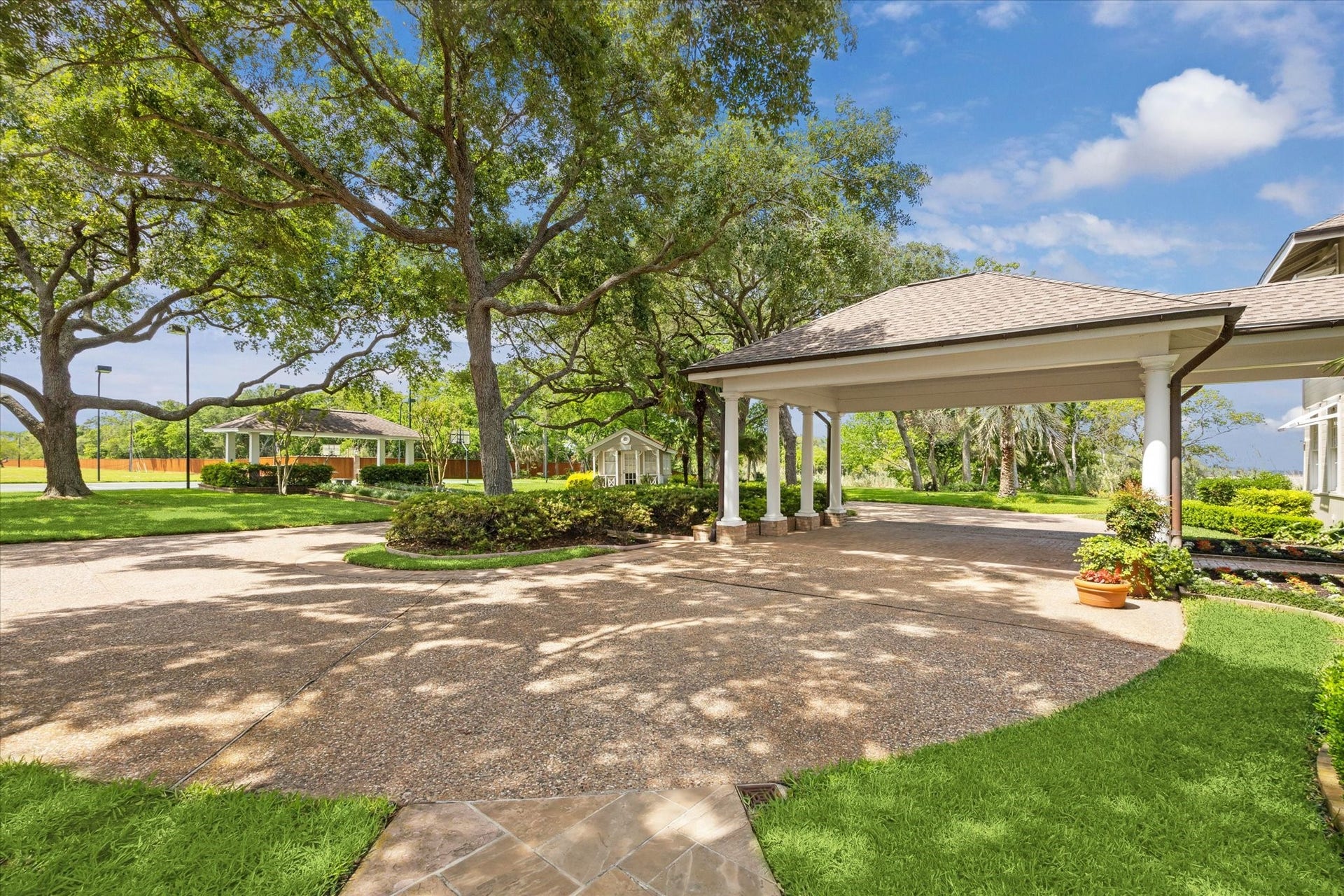 Across from the main residence, discover the "Doll House," a charming structure complemented by a lit tennis court, basketball court, and covered pavilion, offering a variety of recreational options and elegant outdoor living