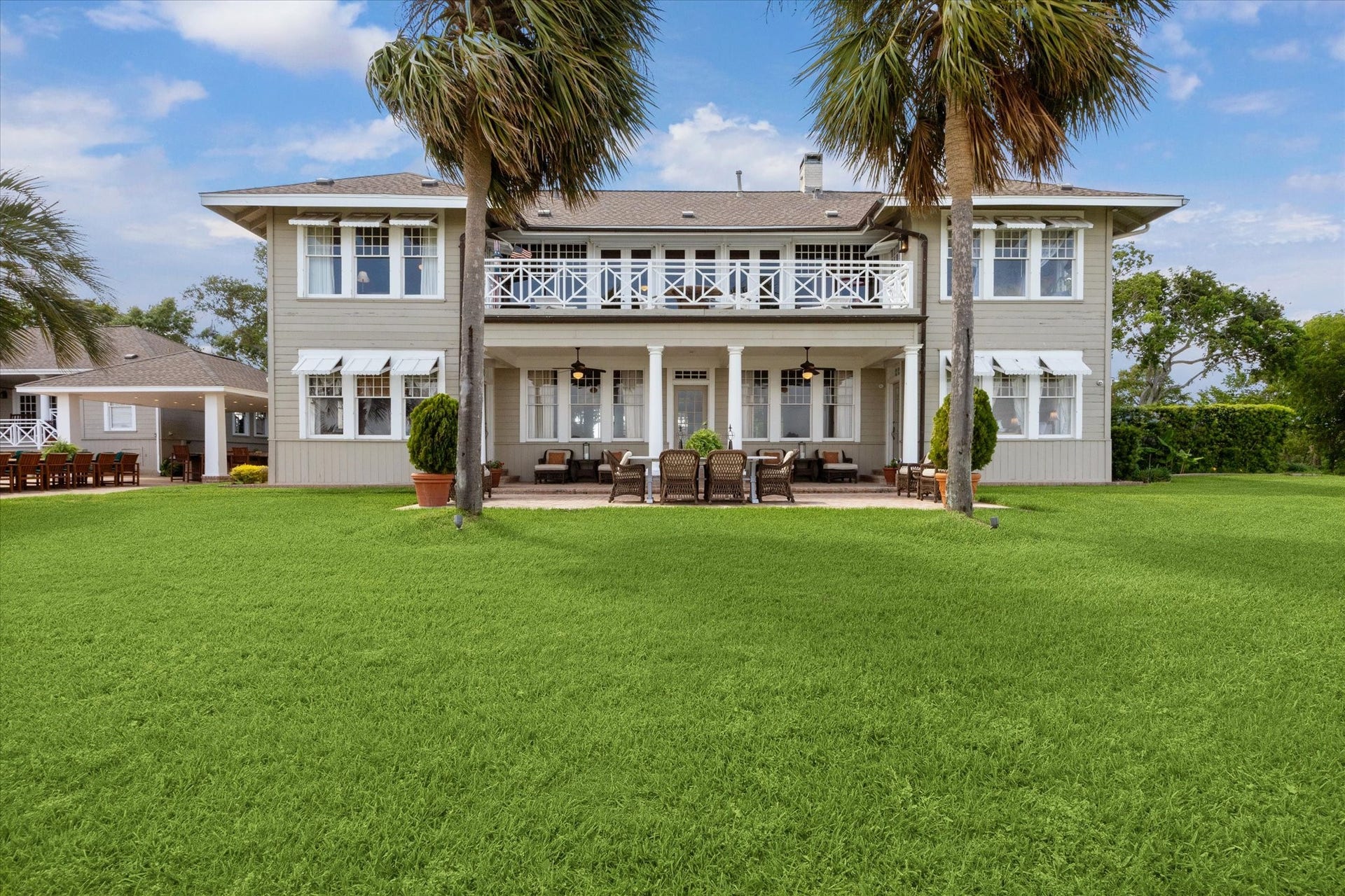 Bayview side of this historic main residence reveals a second-story balcony, a covered patio, and a serene sitting area-all offering sweeping vistas of Galveston Bay.