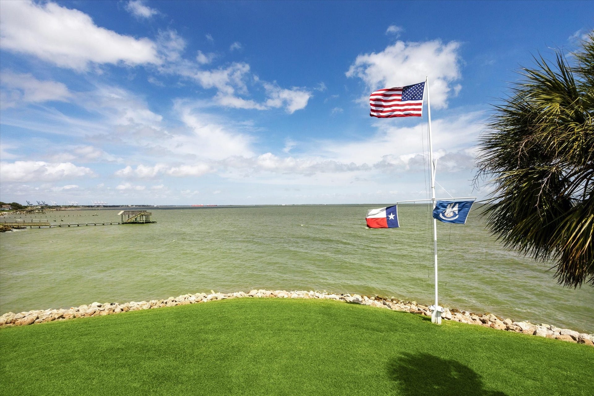 View the custom flagpole taken from the stern of vessel and installed on the property, perfectly complemented by a riprap-lined coastline that stabilizes and protects the shoreline against erosion. This combination enhances both the property's elegance and its waterfront resilience.