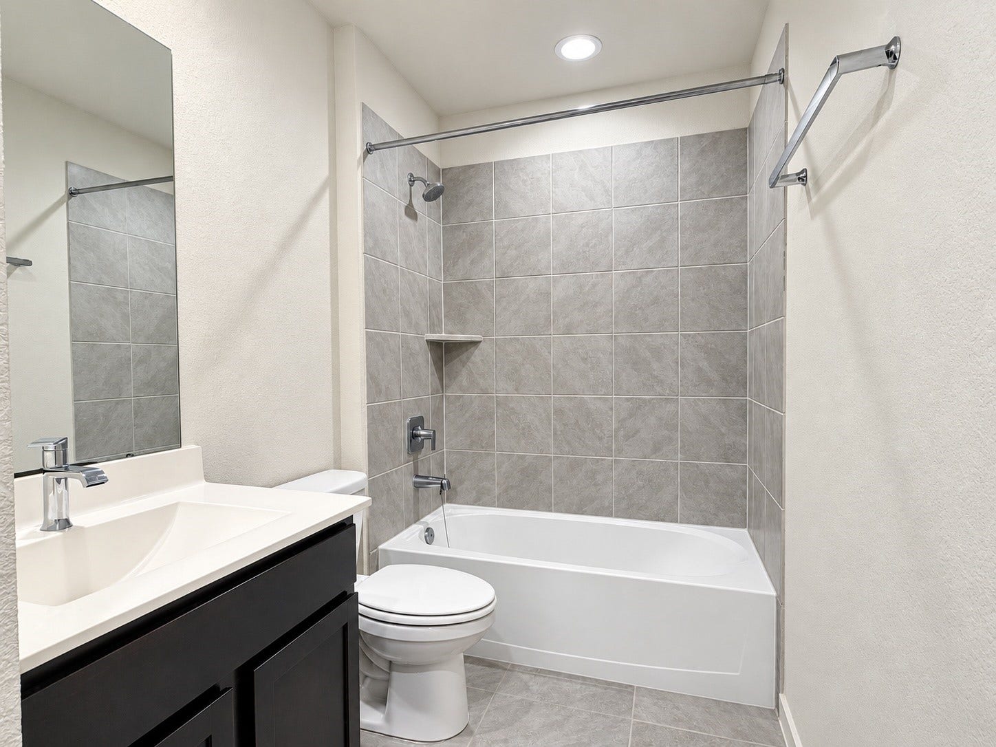 29443 Bryans Manor, Fulshear, TX 77494 Full bathroom featuring a tub and shower combination with gray tile surround, dark vanity cabinetry, and modern fixtures.