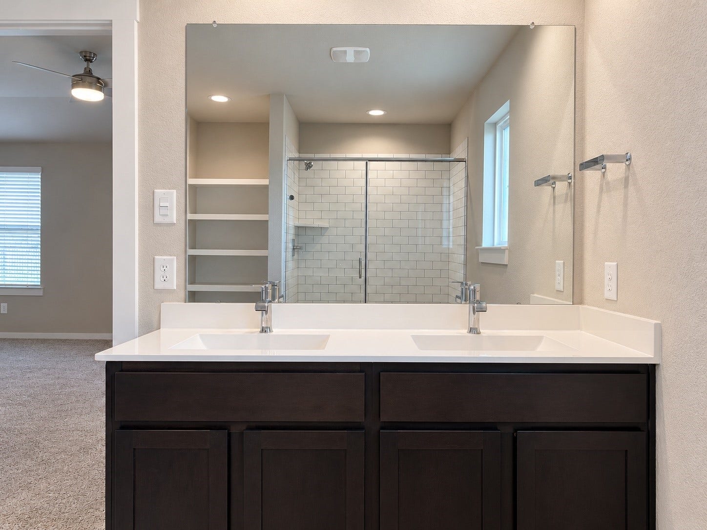 29443 Bryans Manor, Fulshear, TX 77494 Primary bathroom featuring a double-sink vanity, dark cabinetry, expansive wall mirror, and modern fixtures.