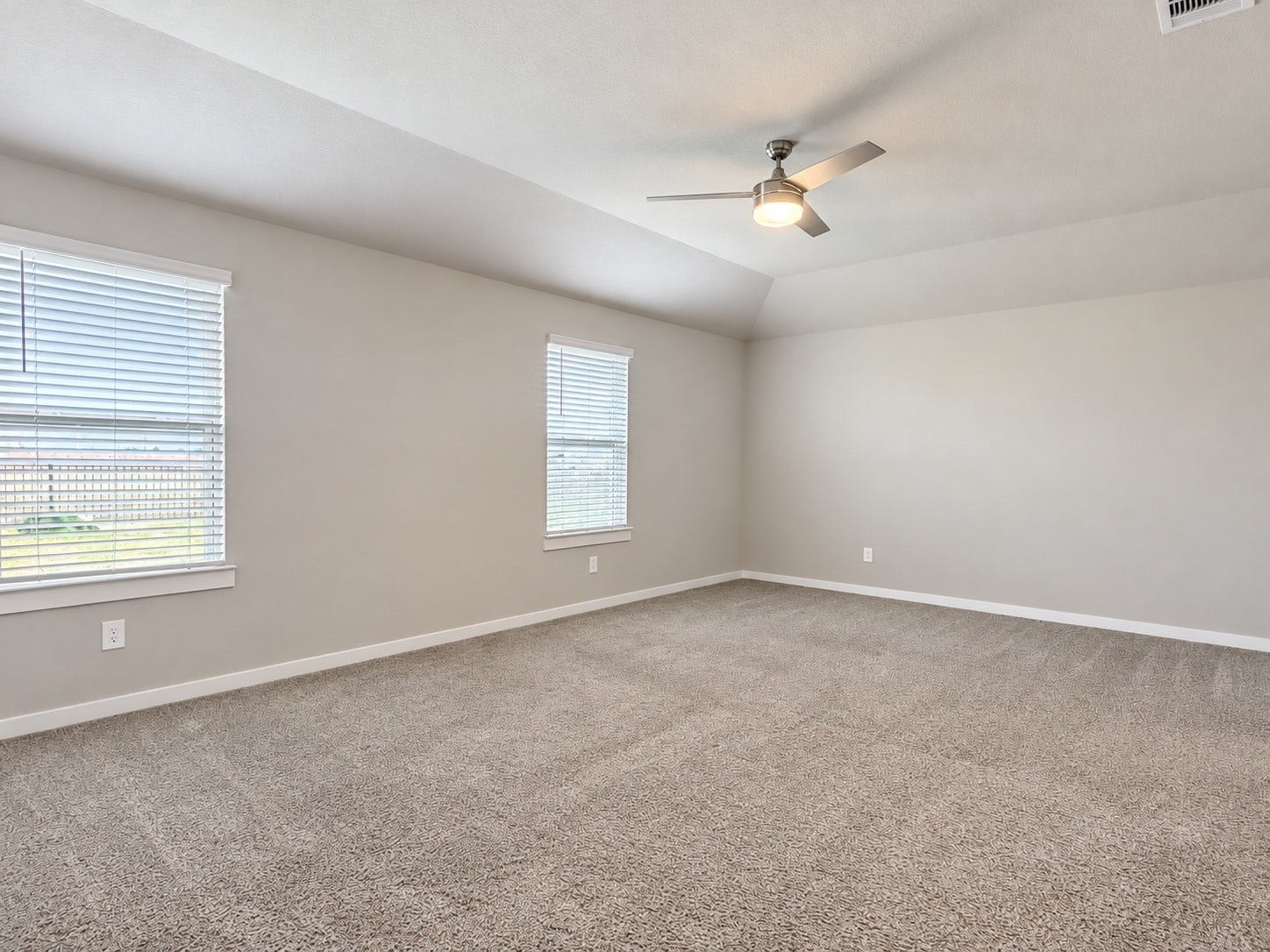 29443 Bryans Manor, Fulshear, TX 77494 Spacious primary bedroom featuring plush carpeting, a ceiling fan with lighting, neutral finishes, and multiple windows.