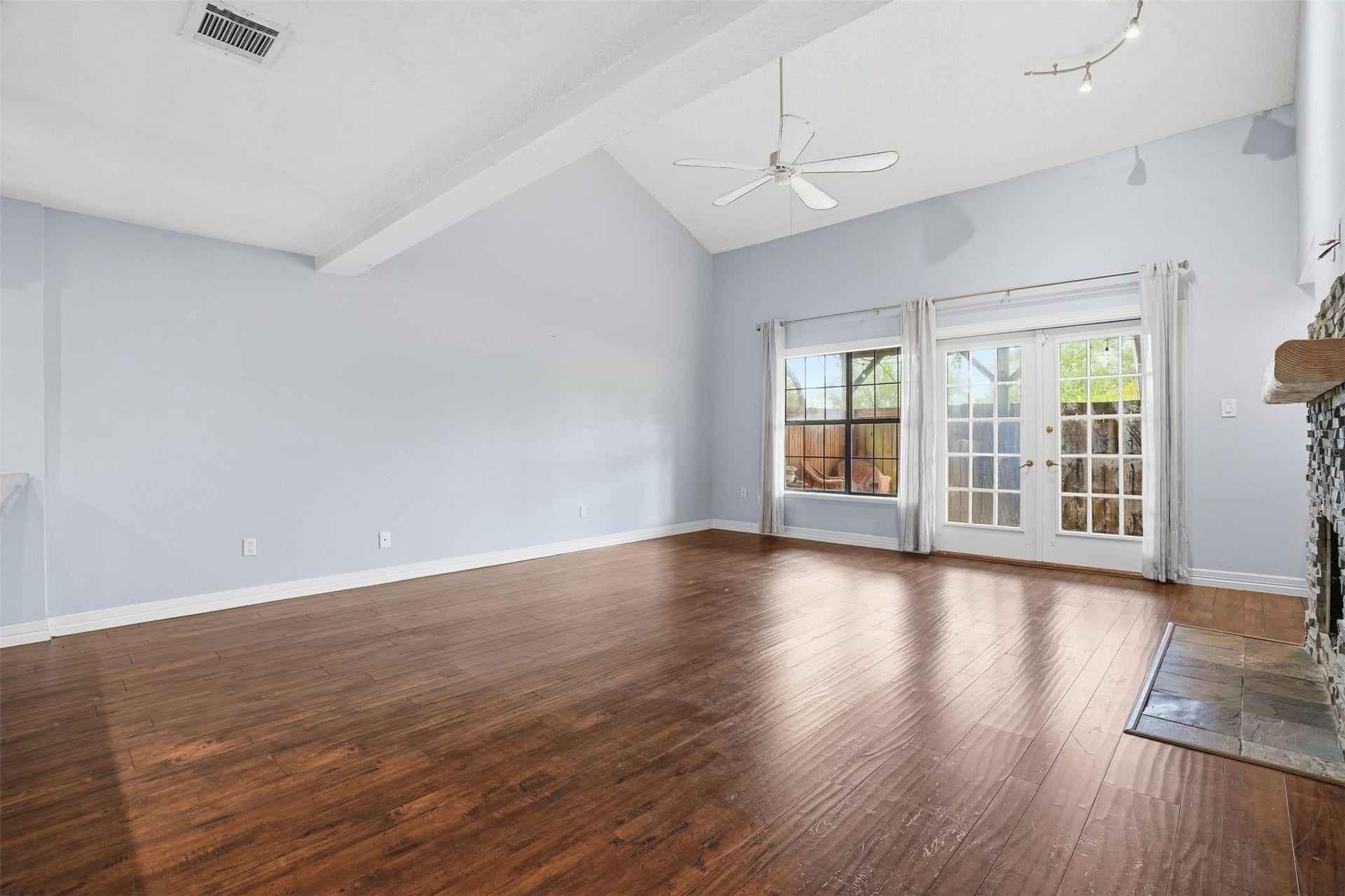 18024 Starboard Drive, Houston, TX 77058 Spacious living room featuring soaring ceilings, wood flooring, and abundant natural light from large windows and French doors leading to the backyard.