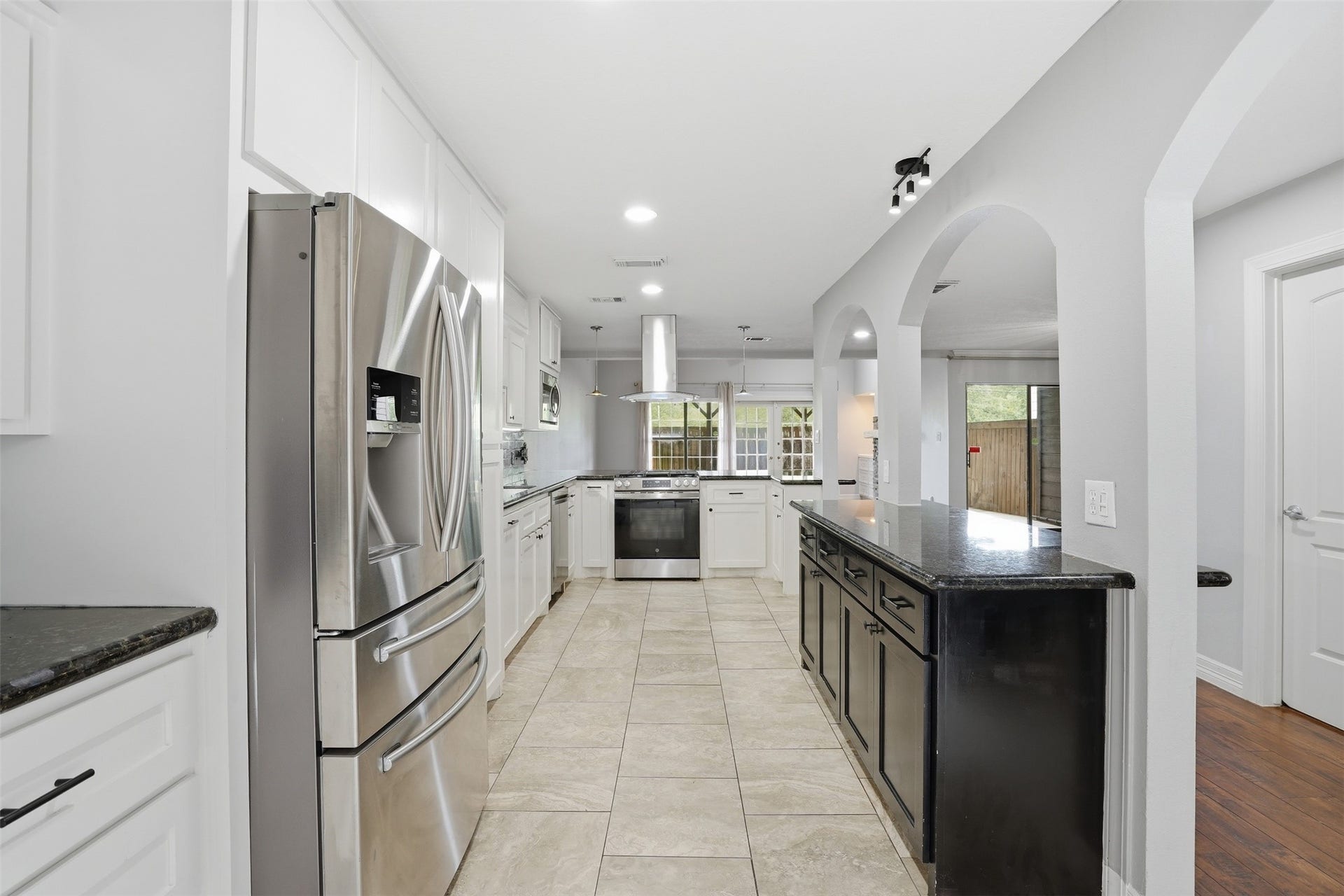 18024 Starboard Drive, Houston, TX 77058 Bright, modern kitchen with granite countertops and ample cabinetry. Arched entryways and an open design create a seamless connection to the spacious living area.