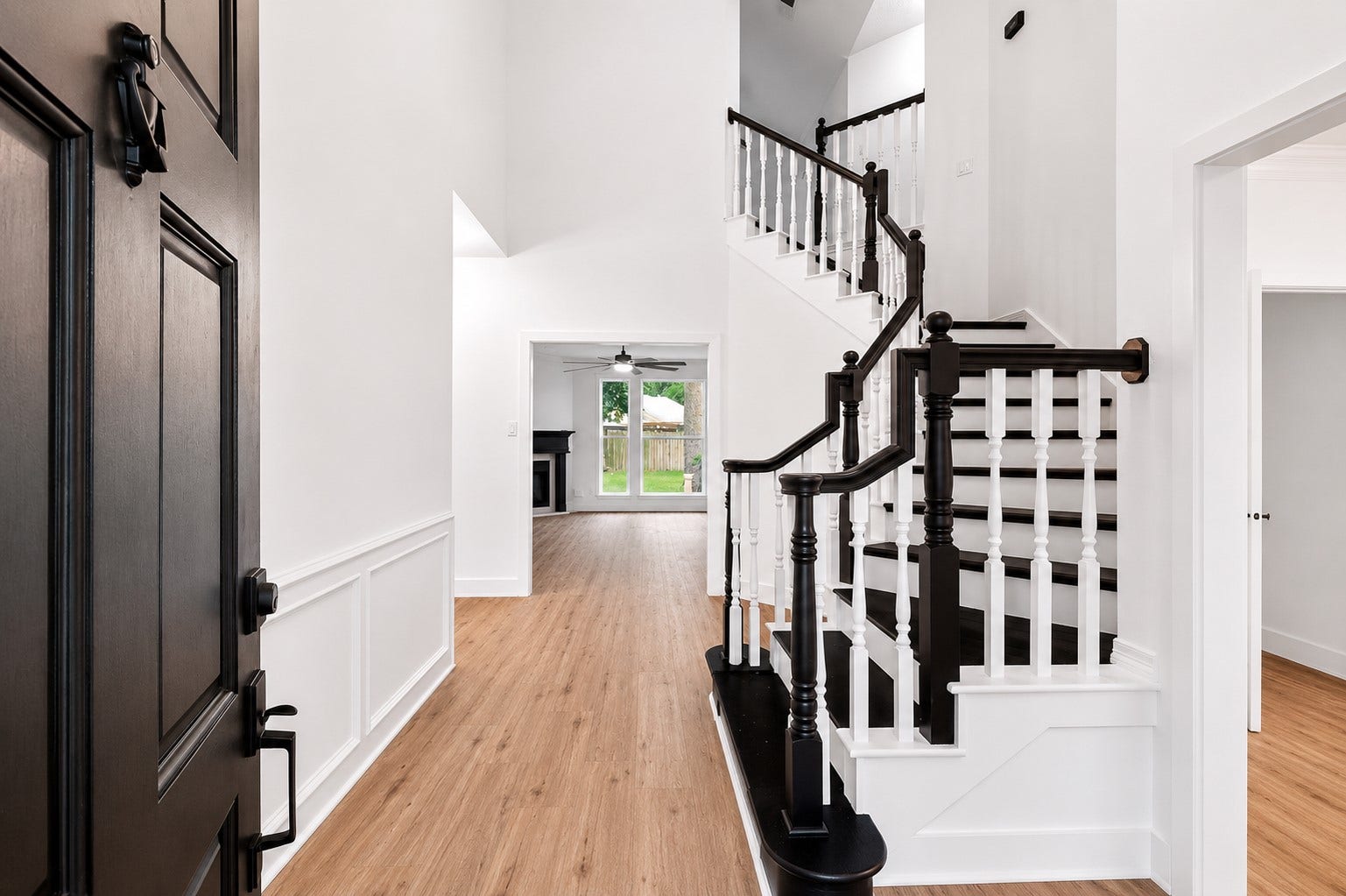 523 Rampart Lane, Conroe, TX 77302 Elegant entryway featuring a striking staircase with dark wood accents and bright, airy interiors leading to a spacious living area.