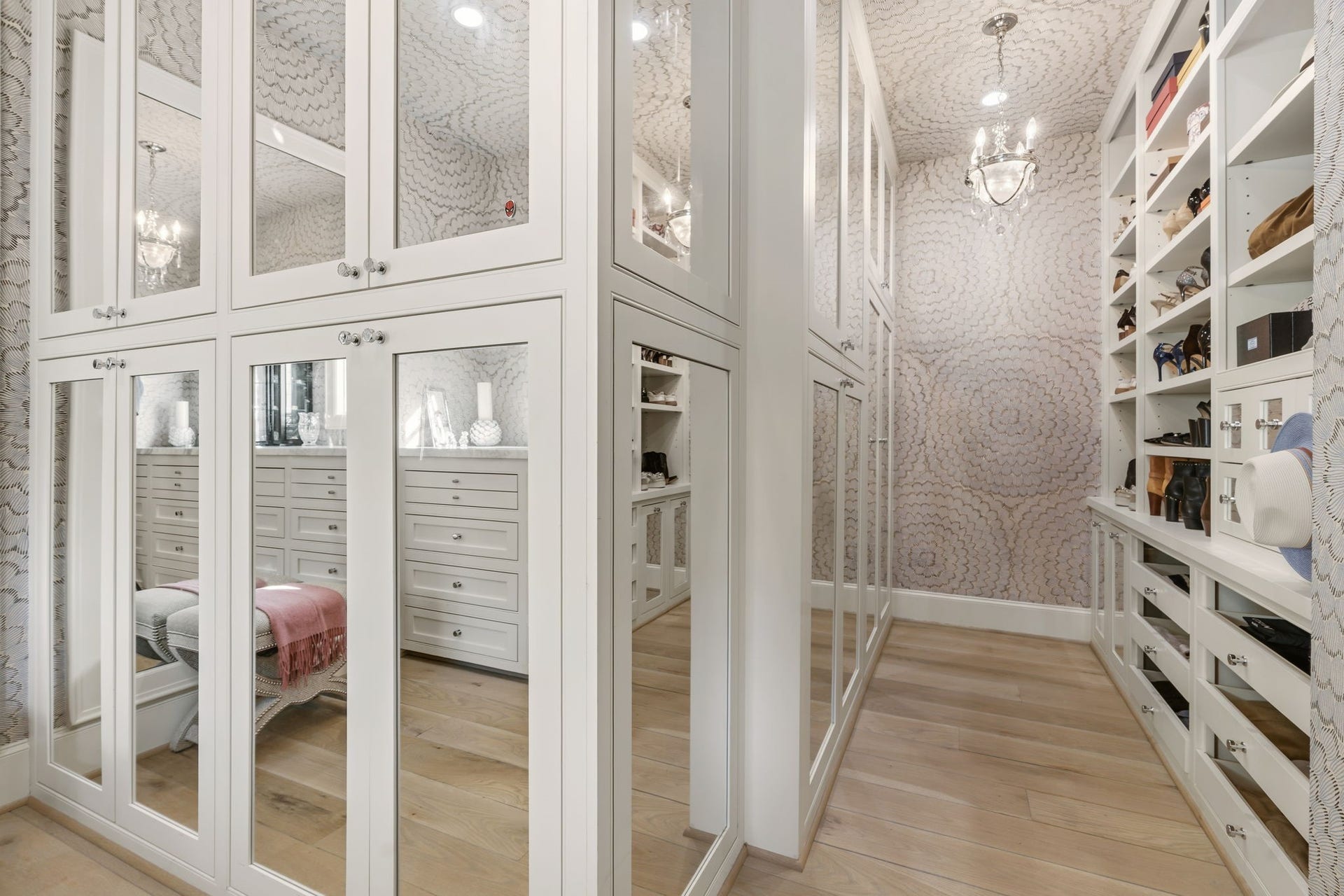 14 Peony Springs Court, The Woodlands, TX 77382 The custom-designed closet offers floor-to-ceiling mirrored cabinetry, built-in shoe shelving & abundant drawer storage, finished with a chandelier.