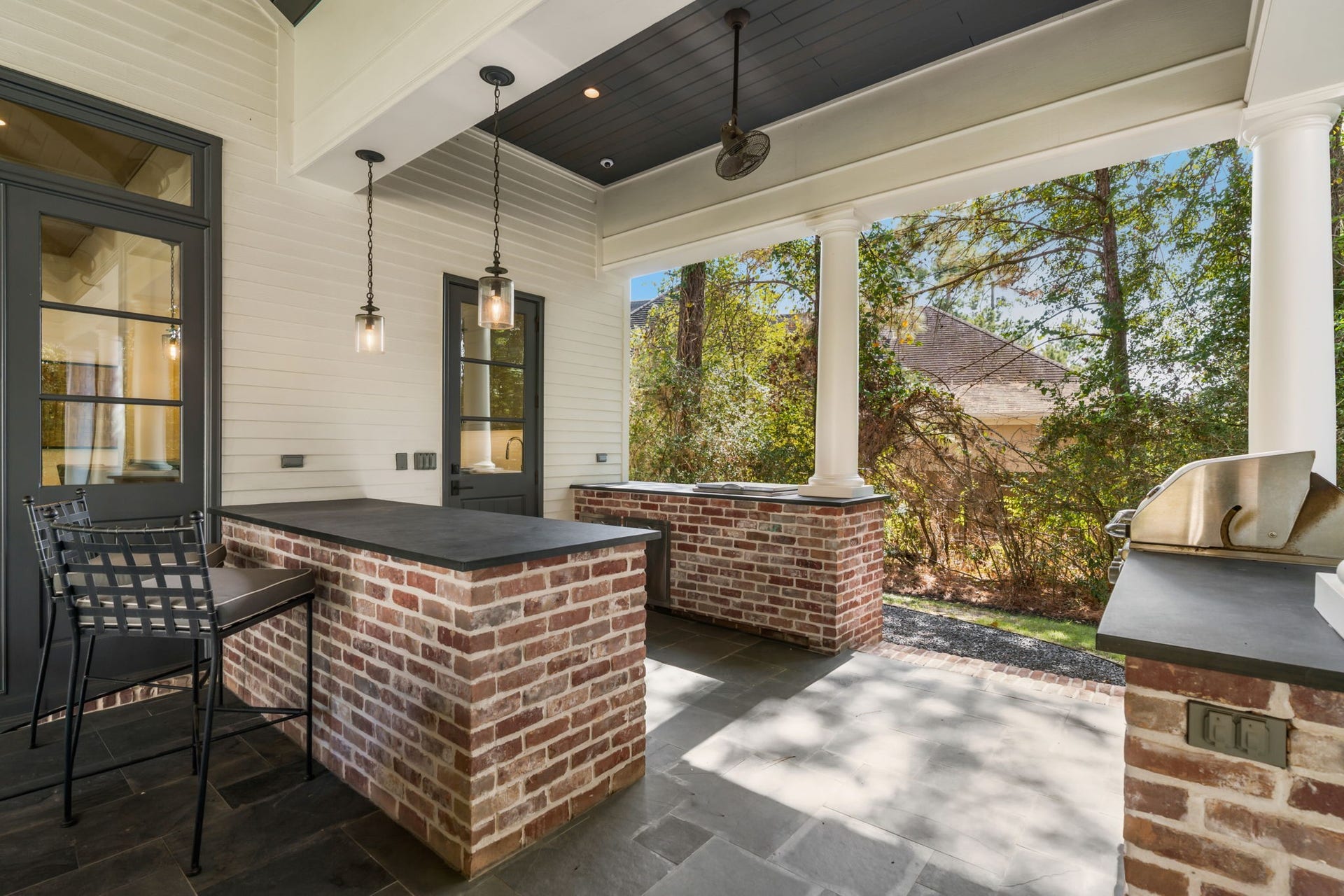 14 Peony Springs Court, The Woodlands, TX 77382 The inside kitchen extends to the continuing slate countertops and storage with a fridge, making the use of the grill easily accessible for entertaining.