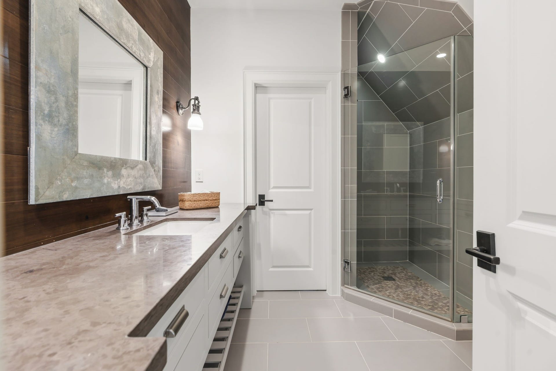 14 Peony Springs Court, The Woodlands, TX 77382 Ensuite bath 3 highlights a nice long vanity with generous countertops and storage pairs well with the extra-tall, deep shower with glass walls, and the stained wood detailed vanity ties to the bedroom."