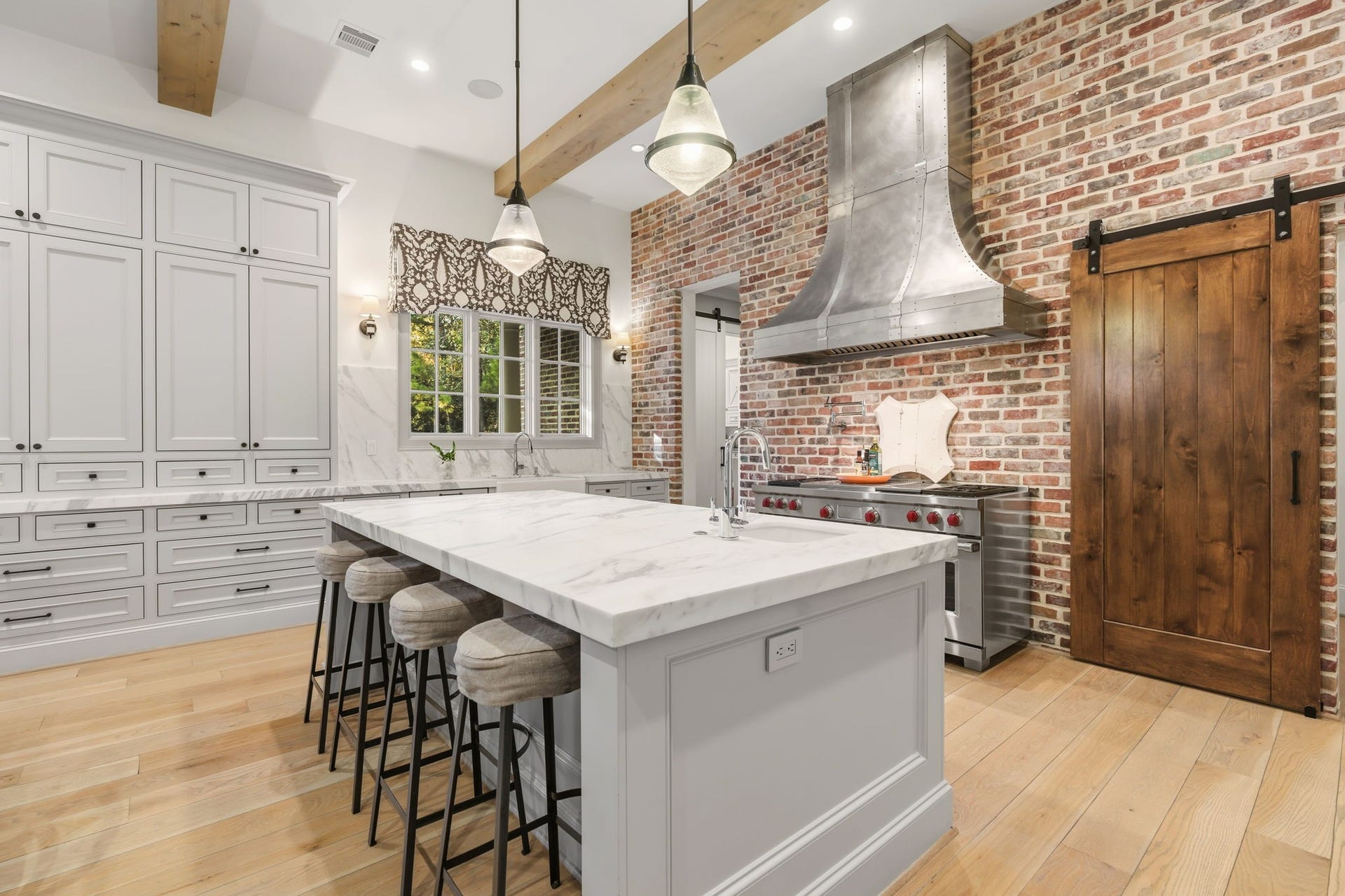 14 Peony Springs Court, The Woodlands, TX 77382 Warm and welcoming - ready to handle any size gathering, the kitchen highlights a brick accent wall with custom sliding door.