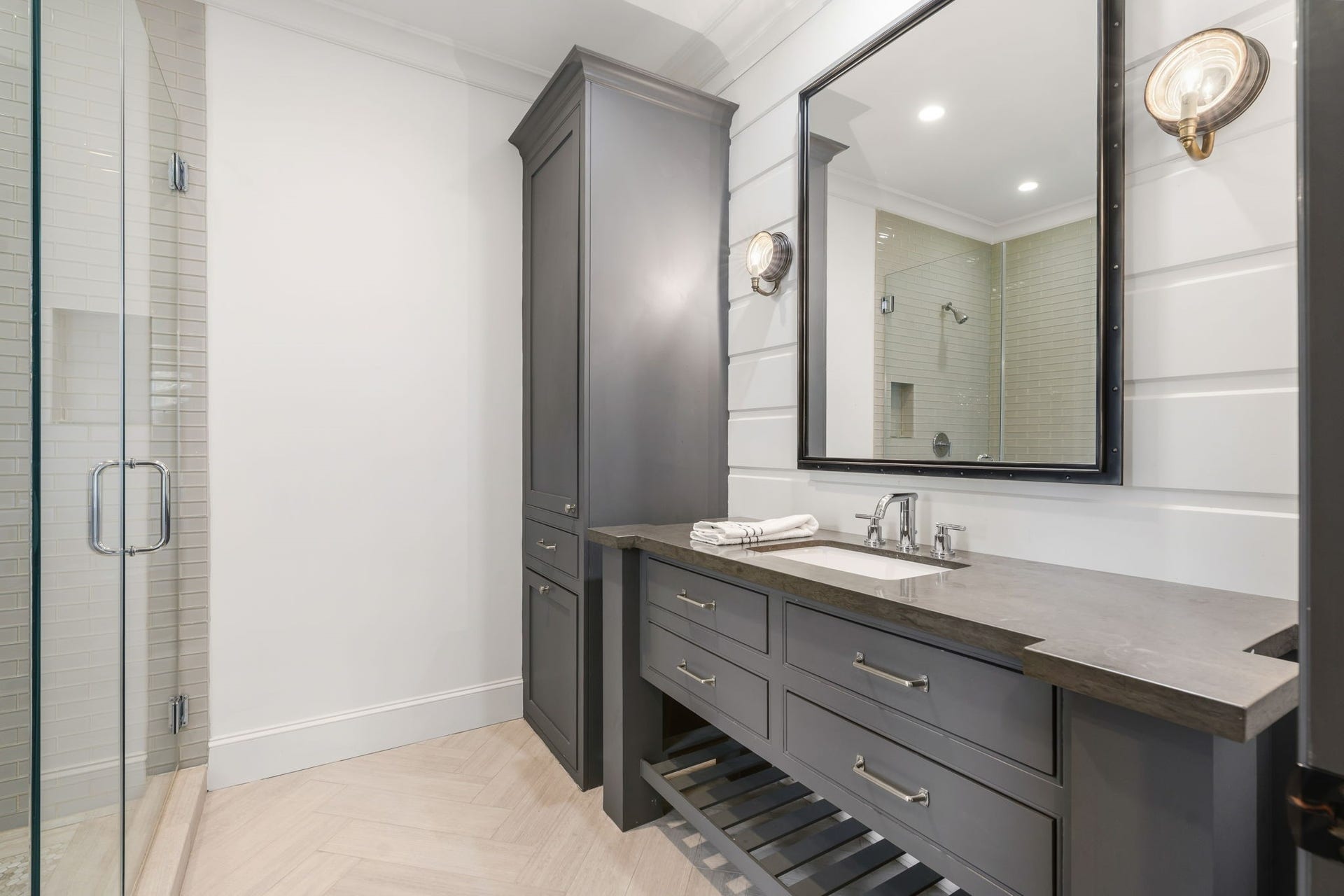 14 Peony Springs Court, The Woodlands, TX 77382 Secondary Bedroom 1 - adjoining bath features Herrigbone silver travertine welcomes you to a generous tongue and groove vanity with ample storage across from an oversized glass-tiled floating shower.