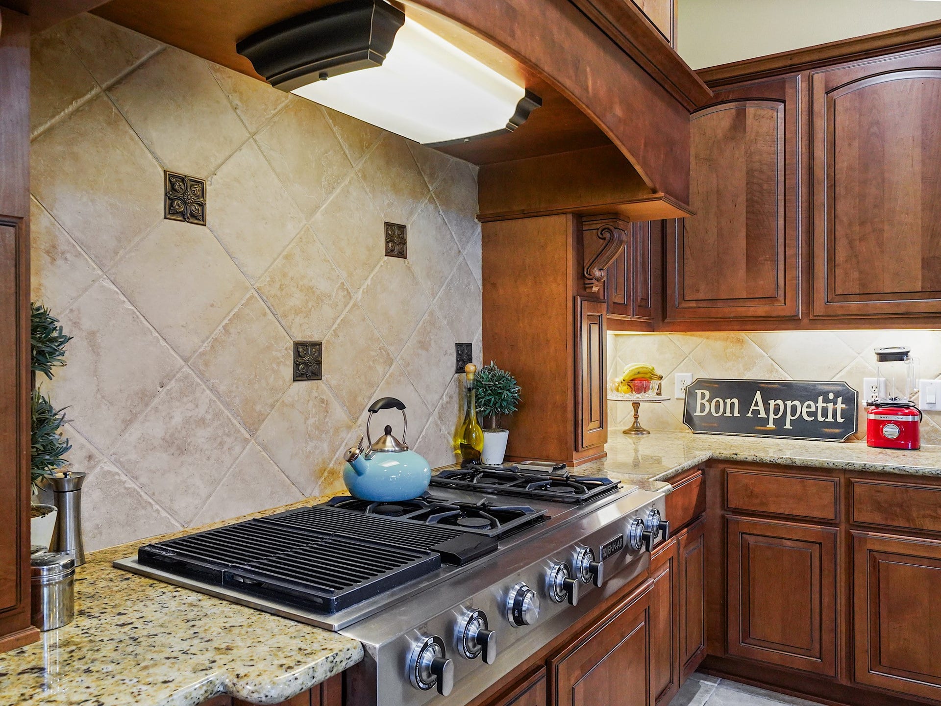 5907 Hawthorne Garden Way, Katy, TX 77494 The JennAir gas cooktop gives the kitchen a chef-inspired focal point, framed by rich Benedettini cabinetry, a detailed tile backsplash, and a substantial vent hood.