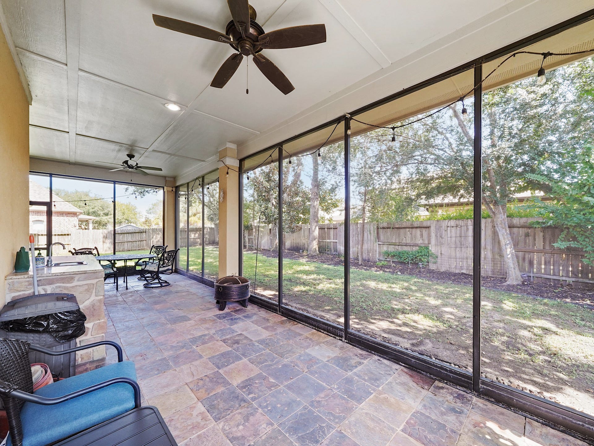 5907 Hawthorne Garden Way, Katy, TX 77494 Slate flooring, ceiling fans, and a covered layout make this screened porch an inviting place to enjoy long Texas evenings.