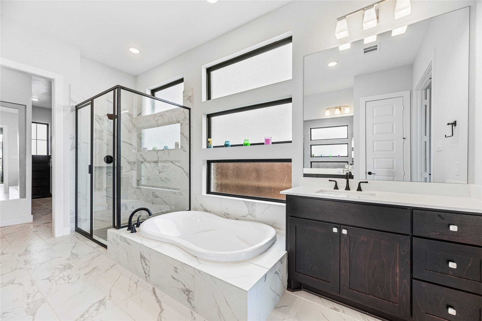 4810 Antler Run Drive, Spring, TX 77386 Elegant bathroom featuring a luxurious soaking tub, a glass-enclosed shower, and a sleek vanity with ample storage, all accentuated by modern fixtures and natural light.